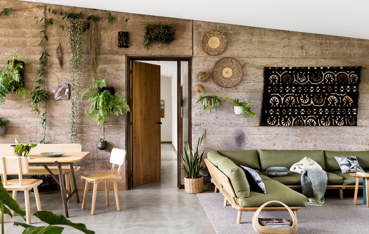De muur is gemaakt van aangestampte aarde en behangen met inheemse vetplanten en varens. Eettafel, bank en stoelen Nicholls Design. Kussen Louise Jones Interiors. Plaid St Albans. Keramische schaal Gordon Hickmott. Hanglamp The Junk Company. Vloerbedekking Cavalier Bremworth. Bijzettafel en bank Nicholls Design, olijfgroene bekleding Sustainable Living Fabrics. Plaid St Albans. Kussens Louise Jones Interiors. Afrikaans wandkunstwerk gekregen. Mand Freedom.