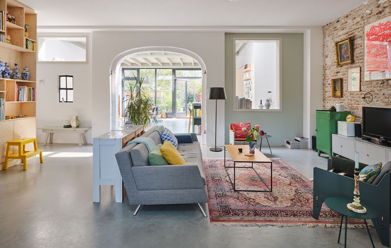 Kastenwand op maat gemaakt van Pools grenen. Trapje Bekväm en tv-kast Lixhult Ikea. Houten bank Piet Hein Eek. Bank Lot van Studio Parade en Fauteuil Katrijn van Floris Hovers via Vrienden. Vloerkleed en groene kast vintage. Ingelijste, neonroze poster Als het leven… Studio Boot.