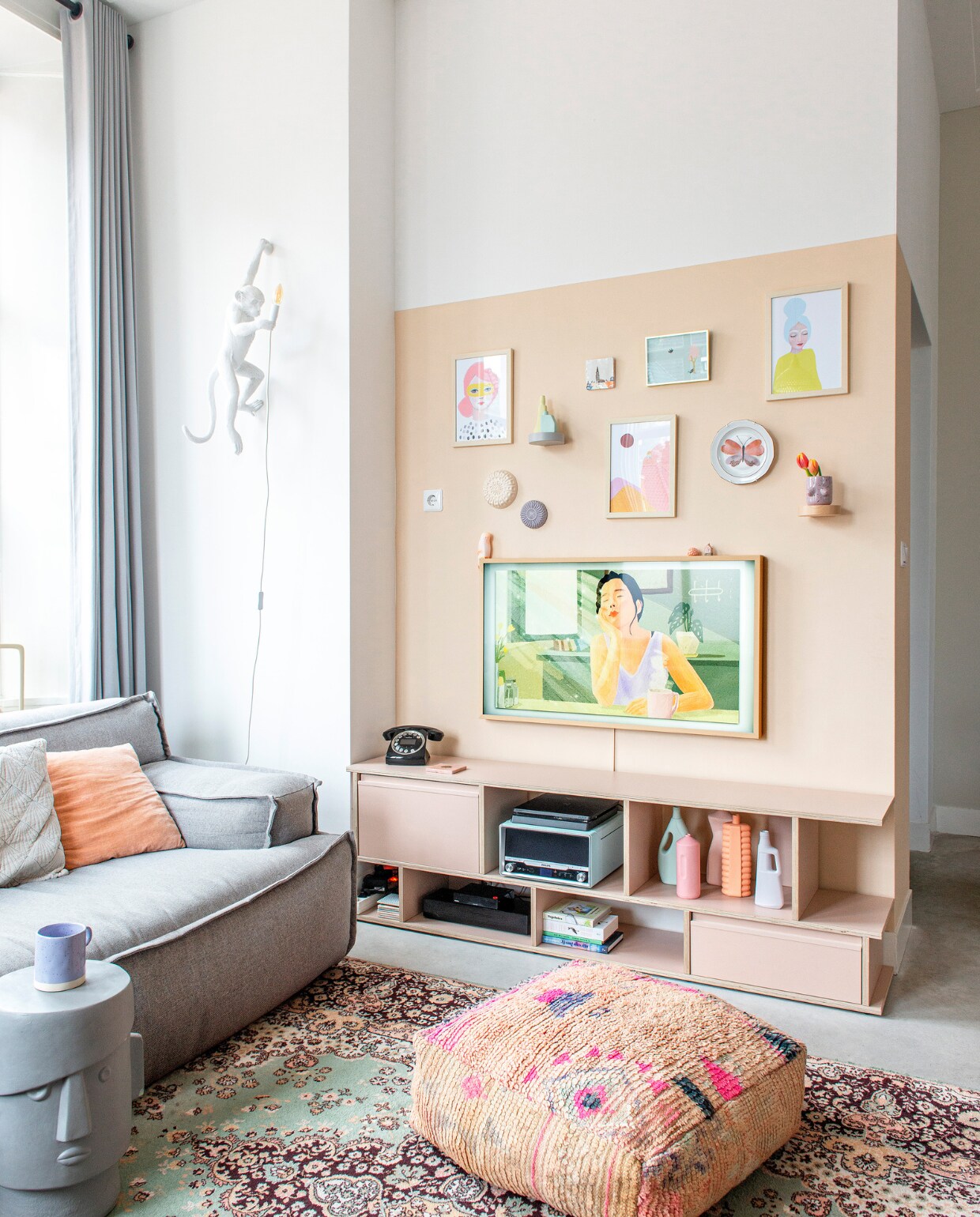 Bank Trendhopper. Televisiekast op maat Tylko. Televisie The Frame van Samsung, telefoon Sage, pick-up Philips. Poef Studio Pure. Kruk Donny van Coco Maison. Vloerkleed vintage. Wandlamp Monkey van Seletti. Kussens Loods 5 en H&amp;M Home. Wandplankjes Ikea. Posters landschap en vrouwen Piet en Kees. Blauwe poster Flow magazine. Wandborden Atelier W, wandbord vlinder Liefs Karlijn. Vazen Foekje Fleur. Tegel Storytiles. Mok Monki. Parkiet Pete Cromer via Prchtg. Huisje vakantiesouvenir. Muurverf Café Latte van Flexa. Betonvloer. Overig onbekend.