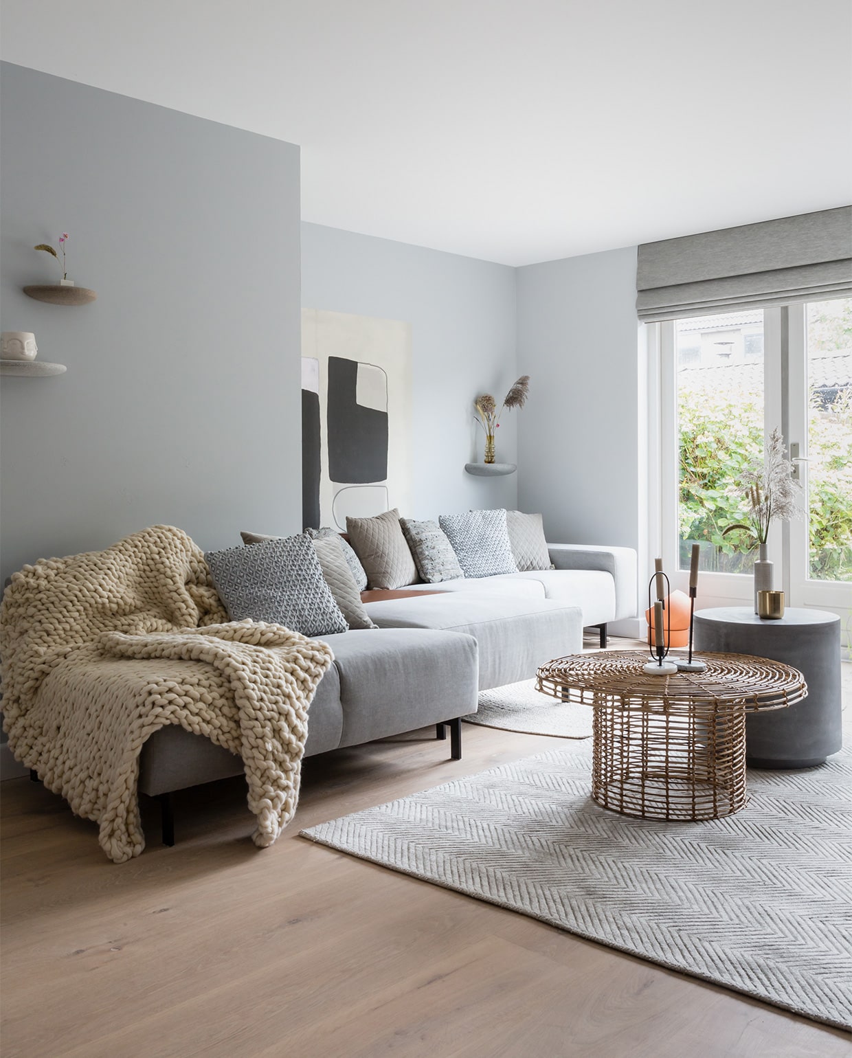 Muurverf Wild Dove, bij de ramen Silver Shadow (flexa.nl). Vouwgordijnen LF035 Simply Grey prijs op aanvraag (jasno.nl). Print aan de muur Wallpower Bold, 150×150 cm (hxb) € 145,- (eijffinger.com). Wandplankjes Stones, set van 3 € 295,- (bogaertslabel.com). Bank prijs op aanvraag, betonnen salontafel € 139,-, salontafel Nature € 209,- (eijerkamp.nl). Vintage stoel € 495,- (bestwelhip.nl). Vloerkleed Viscose Sage € 542,50, rond vloerkleed € 382,50, grof gebreide plaid € 214,50, lichtgrijs leren kussen € 27,50, fluwelen kussen € 26,95 (rocaflor.nl). Pot In your face € 6,99, marmeren kaarsenhouders, per stuk vanaf € 6,99 (housevitaminshop.nl). Vloerlamp € 290,-, vaas Balloon € 46,75, schapenvacht € 79,- (vtwonen.be). Radiatorombouw zelfgemaakt. Droogbloemen, planten (scheepstrabloemen.nl). Vaas € 12,- via kringloopwinkel De Oude Markt Naarden. Overig privébezit.