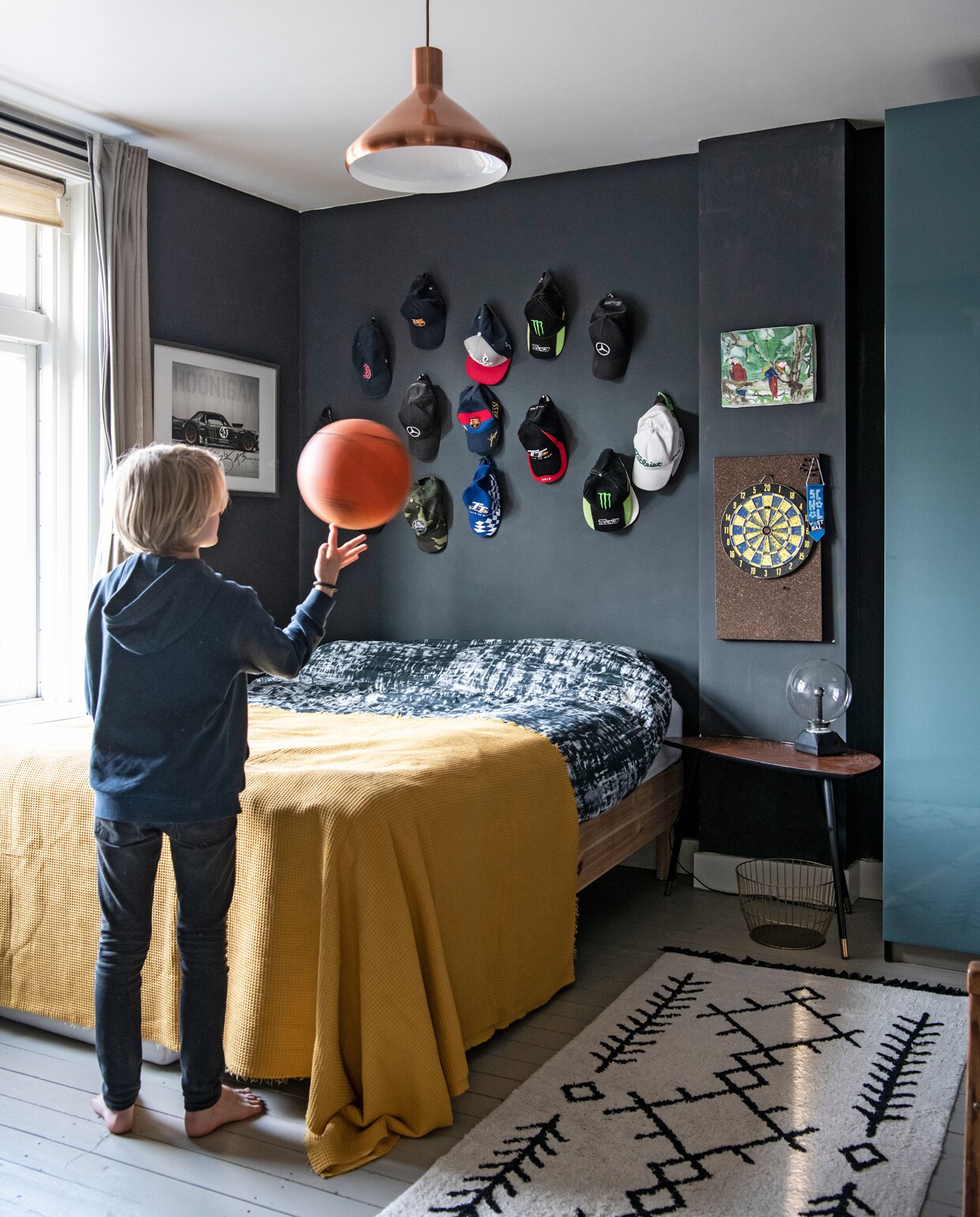 Muurverf Pitch Black van Farrow &amp; Ball. Dekbedovertrek en bijzettafel Ikea. Plaid en vloerkleed Kwantum. Plafond- lamp Karwei. Overig onbekend.