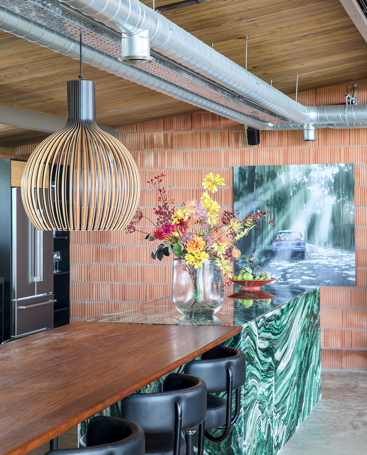 De muur bestaat uit onbewerkte snelbouwstenen. Plafond en eettafelblad van Fraké Noir-hout. Kookeiland van Noors kwartsiet Hafkamp Natuursteen. Barkrukken Arthur Eltink Agencies. Vaas Dutz, kunstbloemen Ten Kate flowers &amp; decorations. Hanglamp Octo Secto Design. Kunstwerk Jan Ros.