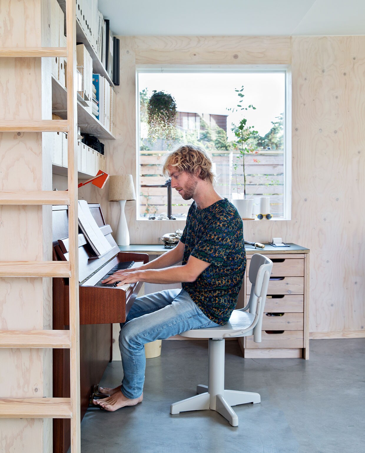 Boekenplanken Ikea, piano Yamaha. Stoel, schemerlamp, kandelaar en plantenpotten kringloop. Bureau eigen ontwerp.