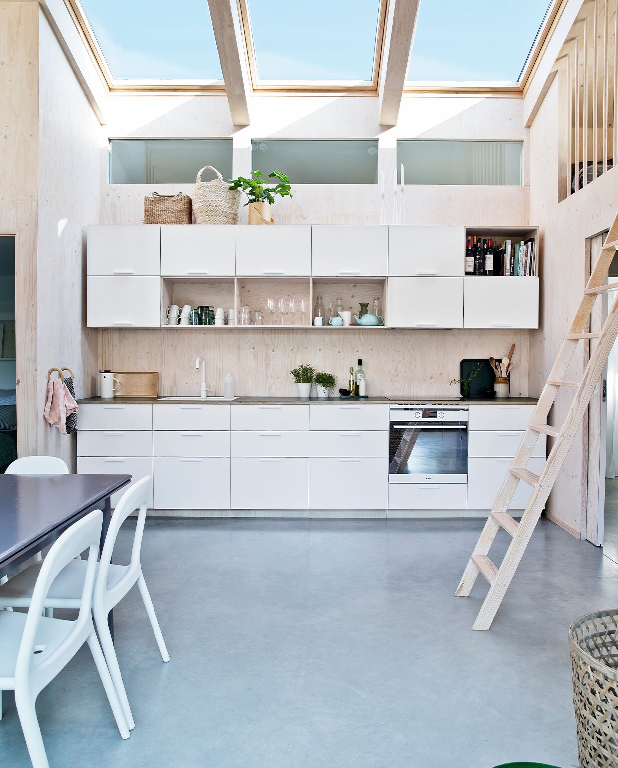 Keukenkastjes Ikea, zelfgemaakt aanrecht van linoleum. Oven Gram. Manden Madam Stoltz, witte koffiekan Stelton, snijplank en witte bekers Ikea, glaswerk Iittala. Serviesgoed, theepot, plantenpotjes kringloop en brocante. Handdoekrekken Hay. Ladder Trævarefabrikernes Udsalg. Eettafel kringloop, stoelen Ikea. Overig herkomst onbekend.