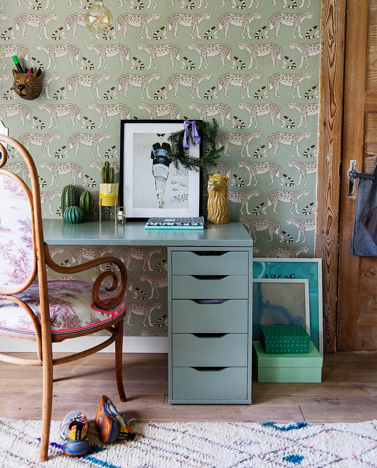 Behang Leopard Walk 109/2009 Cole &amp; Son, bureau zelfgemaakt en -geschilderd met blad van bouwmarkt en ladekastjes van Ikea, stoel Thonet Marktplaats, vloerkleed Living Maroc, panterkop Homestock, hanglamp Calex, cactussen Ikea, geel potje op pootjes cadeau gekregen, plakbandhouder Hema, groene dozen op grond, fotolijsten en poster zwart-wit Ikea, posters vloer dolfijn door Run Jie geschilderd.