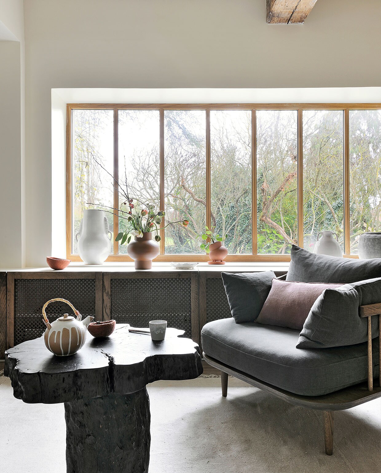 Bijzettafel Opiki AM.PM. Vloerkleed HKliving. Fauteuil Fly Space Copenhagen voor &amp;Tradition. Bruine vaas Bulbe Atelier Germain. Theepot, mok en kom Fleux. Overig onbekend.