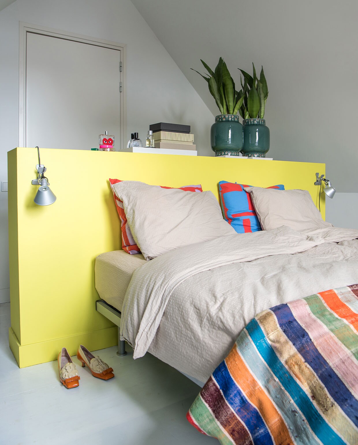 Dekbedovertrekset Crisp Sheets, gekleurde kussens Jantien Baas, plaid Le Petit Nomade, lampen Artemide, opbergdozen Hay, potten Nijhof, schoenen Miu Miu. Verf ombouw RAL 1016.