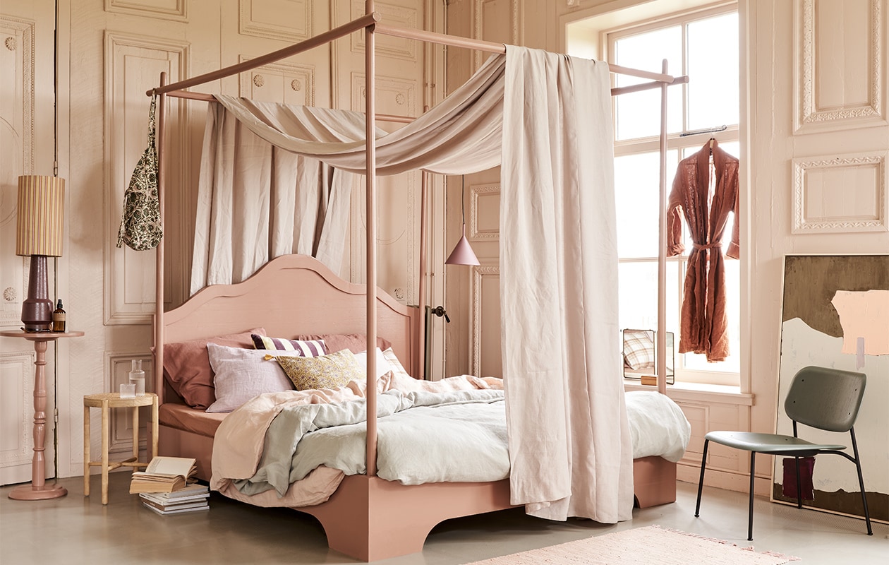 Bed, op maat gemaakt en geschilderd in kleur 86DI64 van D’Imago,180×210 cm prijs op aanvraag, tafeltje op hoge voet geschilderd in kleur 86DI64 van D’Imago, 75 cm (h) € 45,- (com-anders). Hemel Glenmoye van linnen in kleur Nougat van Designers Guild, per meter € 62,- (wva). Dekbedovertrekset van gewassen linnen in kleur Misty Green, 240×220 cm € 319,-, dekbedovertrekset in Dusty Rose, 240×220 cm € 319,-, kussenslopen in Clay Rose, 50×60 cm € 39,95 (yumeko) . Lampenkap Doris van HKliving € 49,95, lampvoet € 159,-, artwork, 100×120 cm € 549,-, hanglamp mat paars € 95,-, velvet kussen met paars-gele strepen € 34,95, houten krukje met webbing zitting € 129,- (hkliving). Tas met print € 40,-, linnen kussen Lilac Rose € 45,-, kussen met bloemenprint in geel Lily Masala € 47,-, roze vloerkleed Chindi Mat Rose, 60×90 cm € 20,- (scandicliving). Kussen met ruitprint € 49,90, roomspray € 29,90, karaf met glas van Ferm Living € 35,90 (letoile.store). Spiegel € 49,- (jolandelijkdewebshop). Fauteuil in groen Soft Edge 10 € 269,- (vtwonen.be).