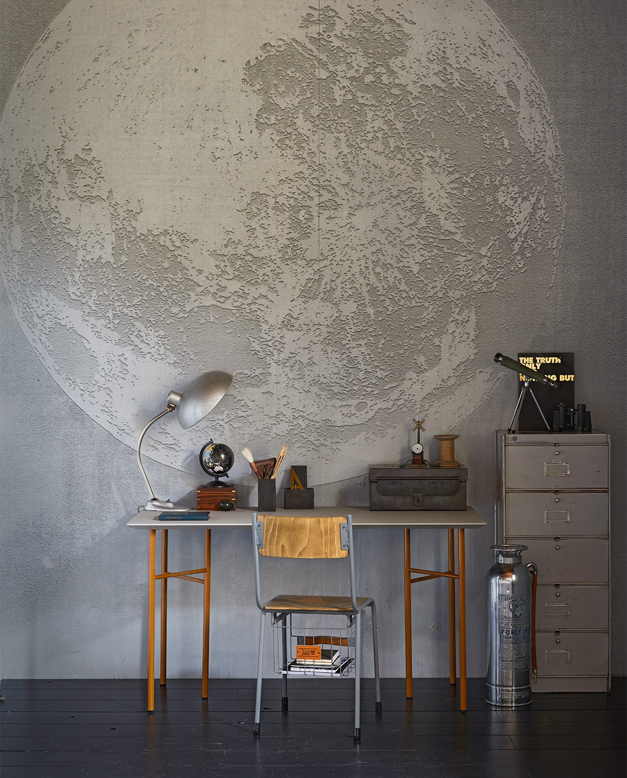 Behang Luna Plena WDLU1702, per m² € 110,- (Wall&amp;decò). Gereedschapskist , € 119,-, brandblusser € 175,-, bureaulamp € 165,-, pennenbak hoog € 14,95, pennenbak laag € 14,95, kleppenkast, 50x40x100 cm (bxdxh) € 195,- (Brût Amsterdam). Storage stoel, hoogte 45 cm € 169,- (www.storage-stool.com). Vintage sterrenkijker € 65,- (All the Luck in the World). Tafelblad Mingle, 135×65 cm € 599,-, okergeel tafelonderstel Mingle van Ferm Living, hoogte 74 cm € 199,- (Kolk en Kolk). Zwarte map met gouden tekst € 10,95 (&amp;klevering). Klosje € 5,-, leren etui met schaar € 15,- (Combitex). Gouden geodriehoek € 37,50 (My Deer Art Shop). Houten doosje met sterrenkijker € 54,95 (De Weldaad). Wereldbol en verrekijker privébezit.