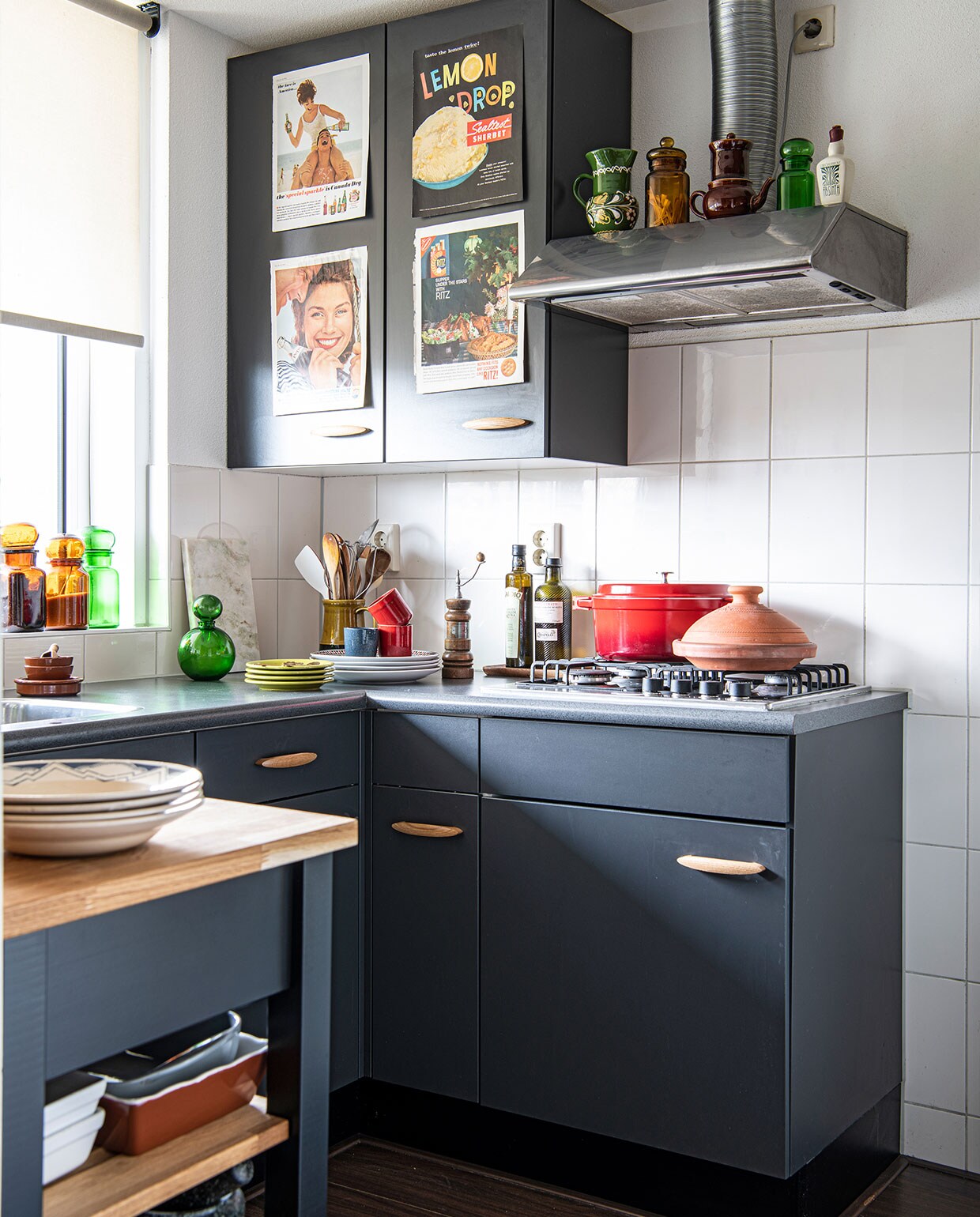 Rode pan Le Creuset, tajine, borden en bruine kommen Dille &amp; Kamille, pepermolen erfstuk, rode espressokoppen H&amp;M Home, kan met lepels vintage. Marmeren plank Flying Tiger, groene kan vintage, groene en bruine kannen in raam tweedehands winkel, borden met blauw antiekwinkel Hans te Kloese. Op de afzuigkap groene vaas, bruine kan en groene kan tweedehands winkel, bruine theepot erfstuk, witte Absinth fles, prints op keukenkasten uit Amerikaanse tijdschriften. Overig onbekend.