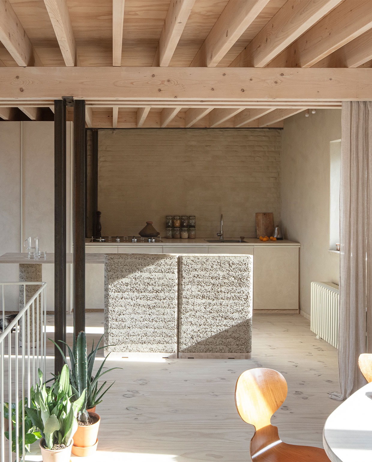 Keuken zelfontworpen en gebouwd met kranen en wasbak van Reginox, apparatuur Smeg, schakelaars Jung. Het muurtje op de voorgrond is van rammed earth, een materiaal van hergebruikte grondstoffen van BC Materials. Gietijzeren radiator geërfd van Hanne’s oma.