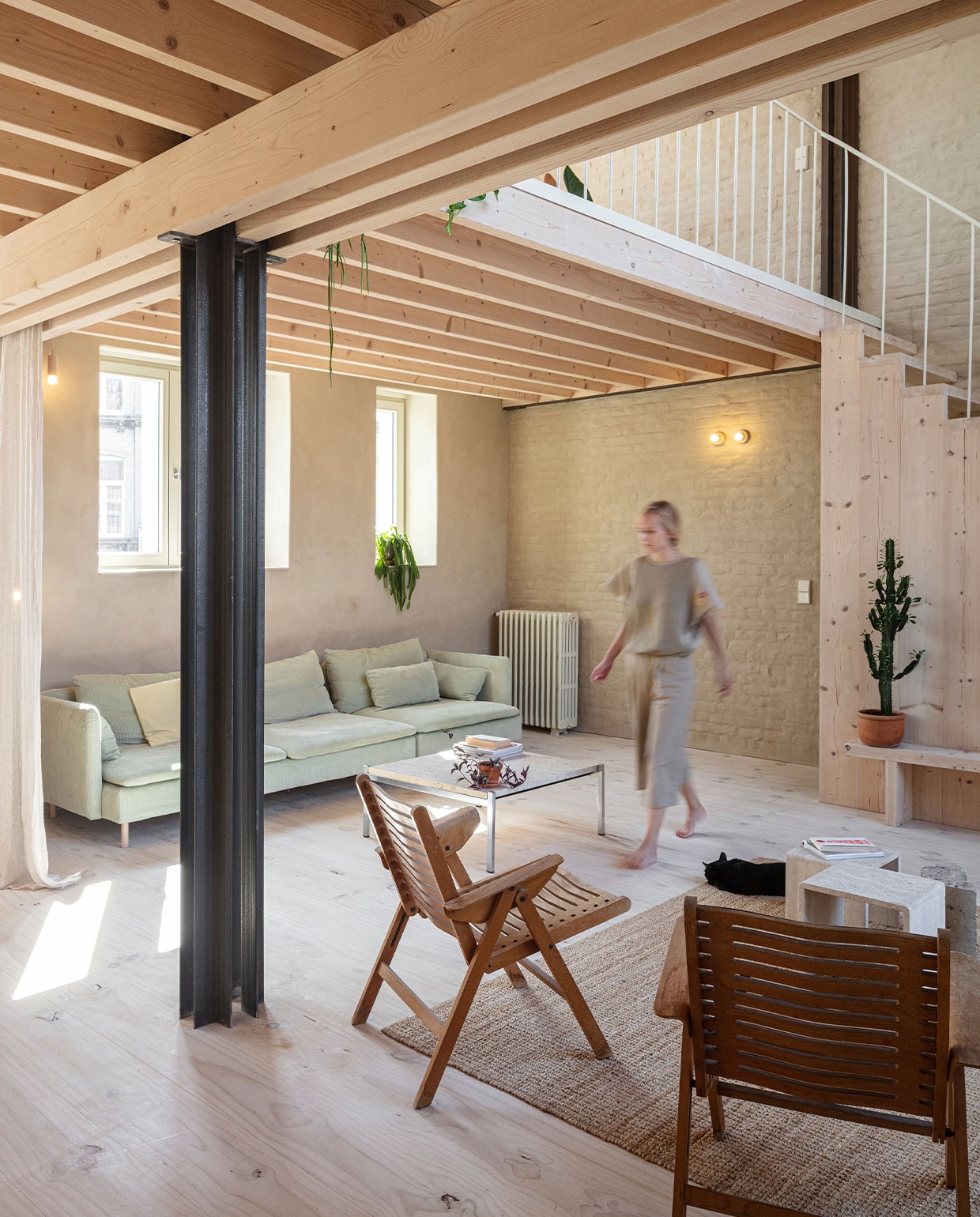 Stoelen Niko Kralj. Salontafel en travertijnen bijzettafels tweedehands. Vloerkleed en bank met hoes van Bemz Ikea. Gordijnen Zara Home. Houten bank zelfgemaakt. Vensterbanken Oslo White steenstrips van Roben. Lampen gemaakt door de vader van Nicolas. Gietijzeren radiator geërfd van Hanne’s oma.