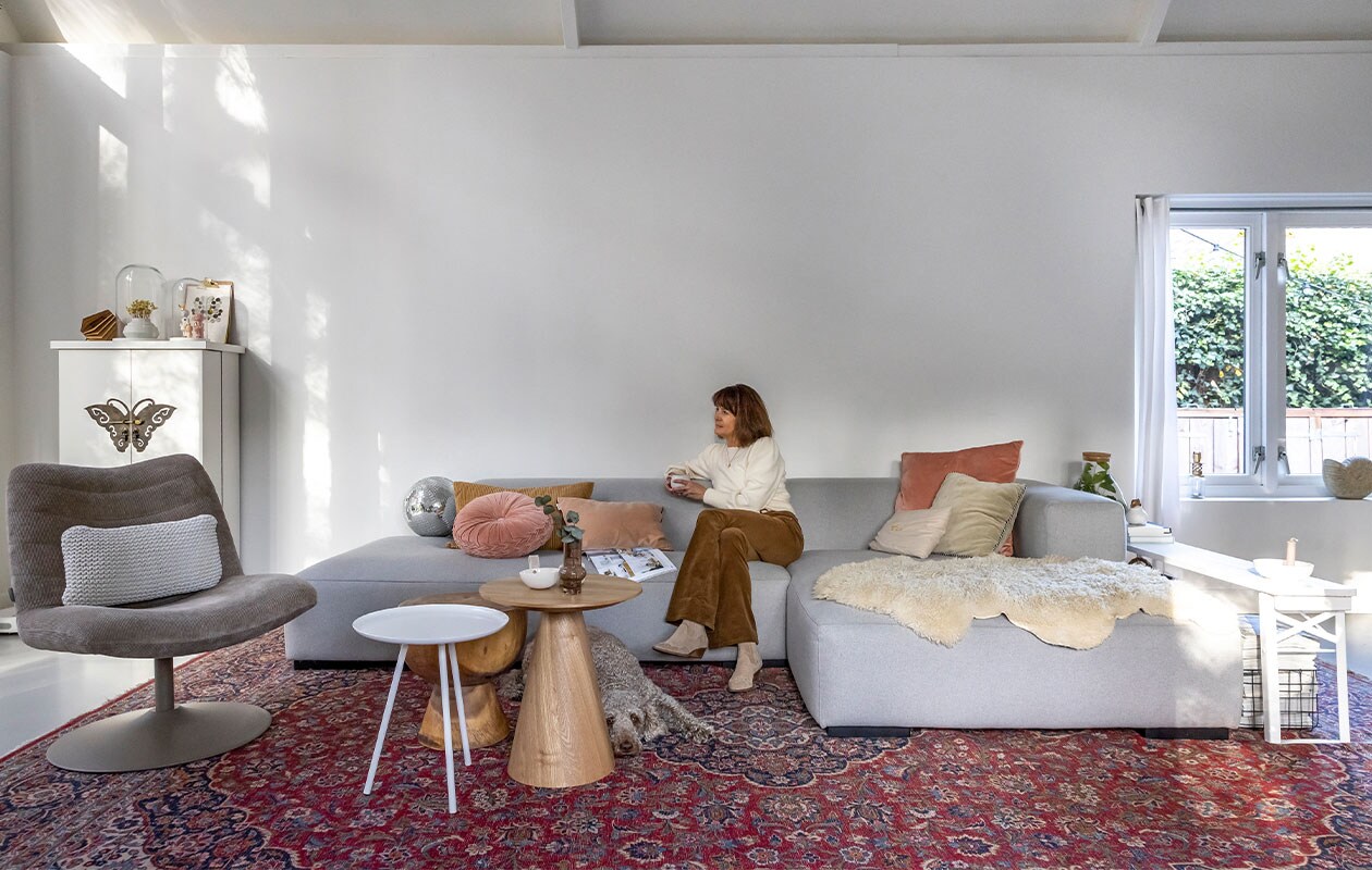 Bank Koozo, geel kussen en gordijnen Ikea, rond kussen en kandelaar in vensterbank Loods 5, lichtroze kussen Sissy-Boy, roze kussen rechts Dutch Decor, zandkleurig kussen Atelier Pomme, lichtgroen kussen, grote houten tafel, draadstaalmand en discobal Kwantum, kleine houten tafel Marktplaats, witte tafel Zuiver, schapenvacht Zalando Lounge, kleed overgenomen van vorige bewoners, vlinderkast Het Kabinet, muur ral 9016, stoel Zuiver, kussen in stoel Goround interior, grote stolp Mica Decorations, vaas Hella Duijs, kleine stolp Hema, pop in stolp links Lammers&amp;Lammers, pop rechts atelier W, lamp Tjalle en Jasper, klembord Hema, poster Jurianne Matter, witte schaal Jet at Home, vaas Huizedop via Kruidvat, biertafel herkomst onbekend, kandelaar Storefactory, plant in glazen fles cadeau gekregen.