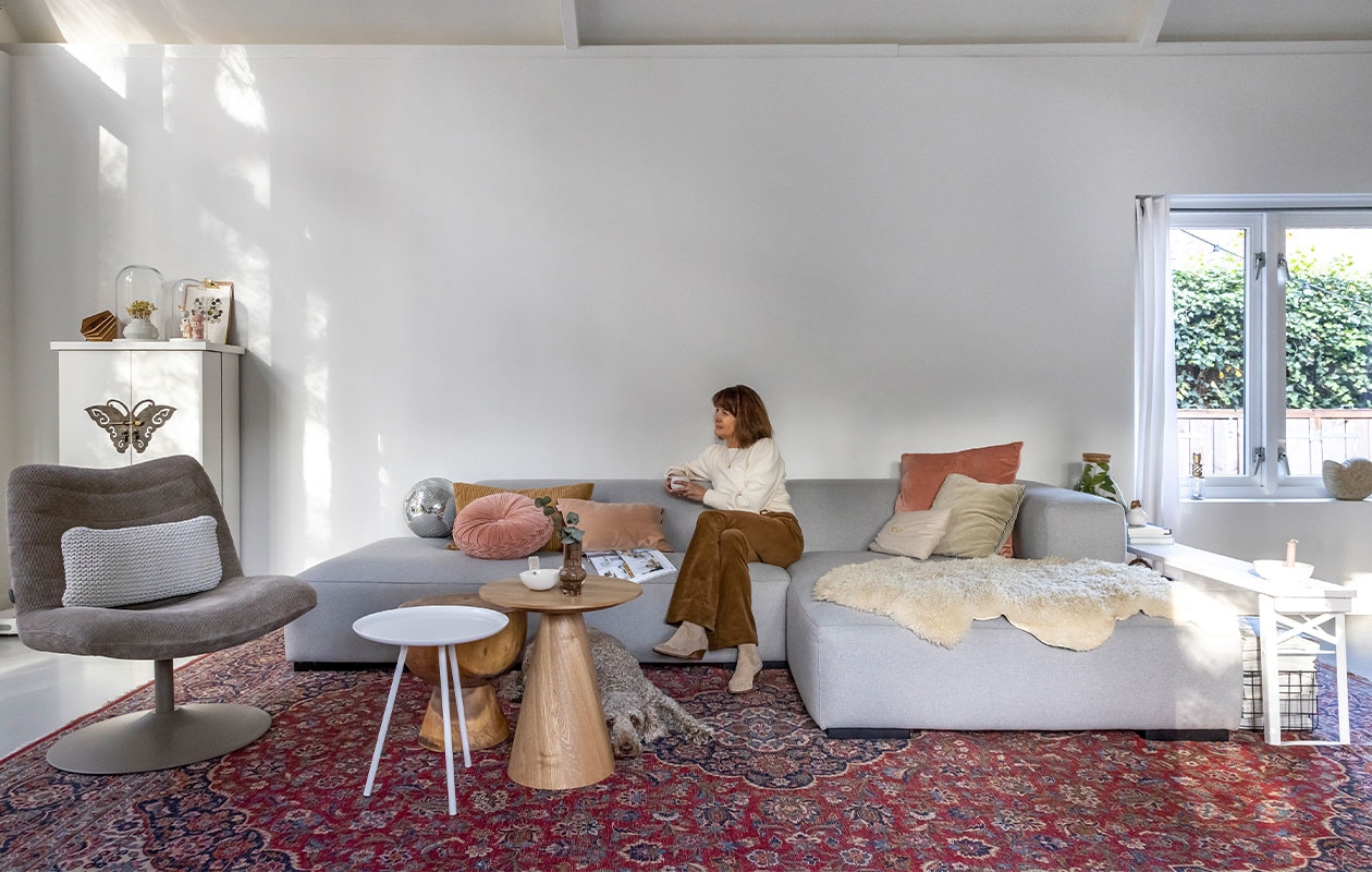 Bank Koozo, geel kussen en gordijnen Ikea, rond kussen en kandelaar in vensterbank Loods 5, lichtroze kussen Sissy-Boy, roze kussen rechts Dutch Decor, zandkleurig kussen Atelier Pomme, lichtgroen kussen, grote houten tafel, draadstaalmand en discobal Kwantum, kleine houten tafel Marktplaats, witte tafel Zuiver, schapenvacht Zalando Lounge, kleed overgenomen van vorige bewoners, vlinderkast Het Kabinet, muur ral 9016, stoel Zuiver, kussen in stoel Goround interior, grote stolp Mica Decorations, vaas Hella Duijs, kleine stolp Hema, pop in stolp links Lammers&amp;Lammers, pop rechts atelier W, lamp Tjalle en Jasper, klembord Hema, poster Jurianne Matter, witte schaal Jet at Home, vaas Huizedop via Kruidvat, biertafel herkomst onbekend, kandelaar Storefactory, plant in glazen fles cadeau gekregen.