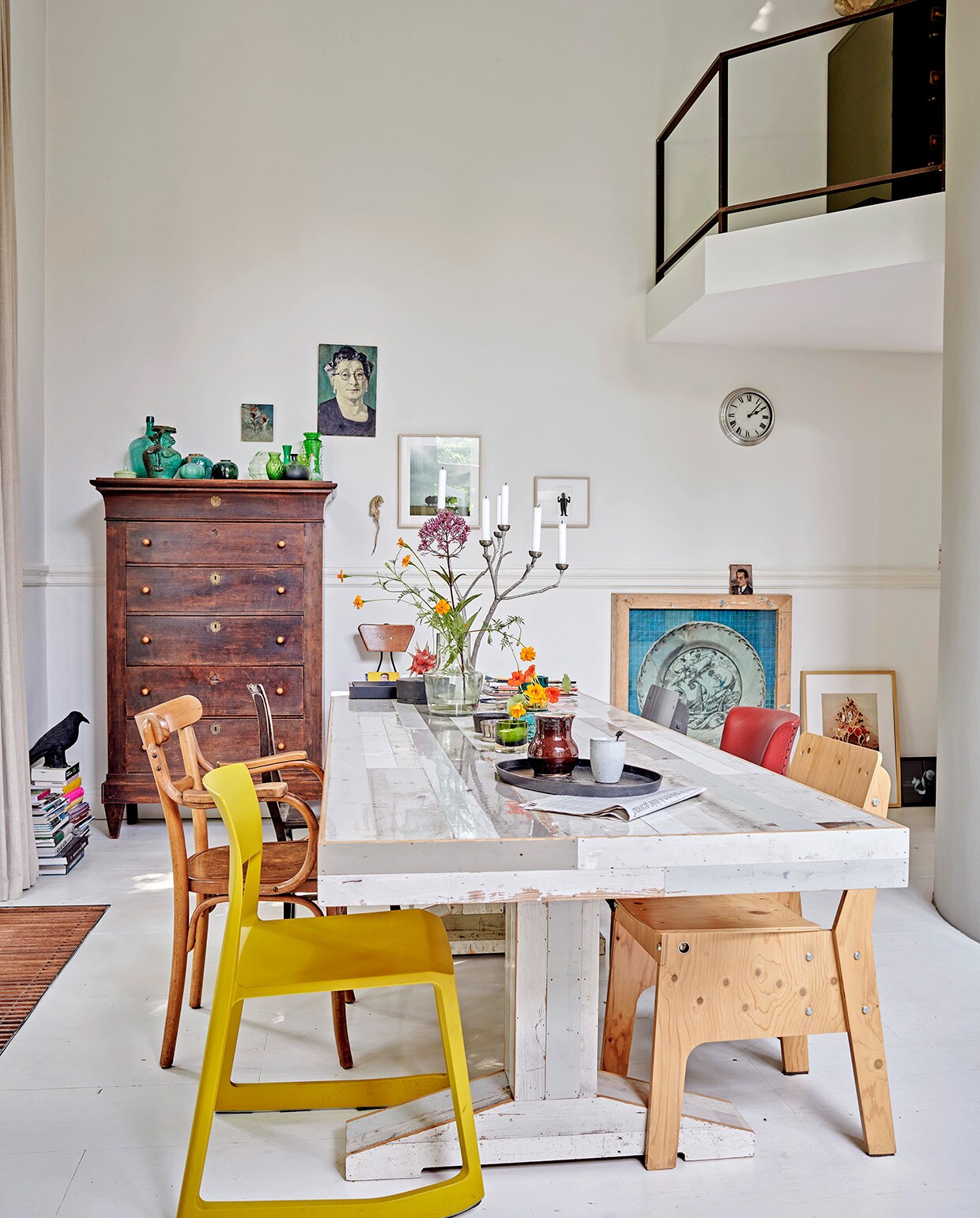 Oude grenenhouten vloer, wit geschilderd. Gele stoel Tip Ton van Vitra via Van Duivenboden. Eettafel Kantinetafel en stoel rechts voor Piet Hein Eek. Kandelaar Twiggy Large Sjakie’s. Kast Chiffonnière. Vogel raaf en dienblad Pols Potten. Kunst transfer op rijstpapier in houten lijst van Laurien Mulder. Papiermaché rat van Caroline de Bruijn. Vaas op tafel MrsBloom. Overig herkomst onbekend.