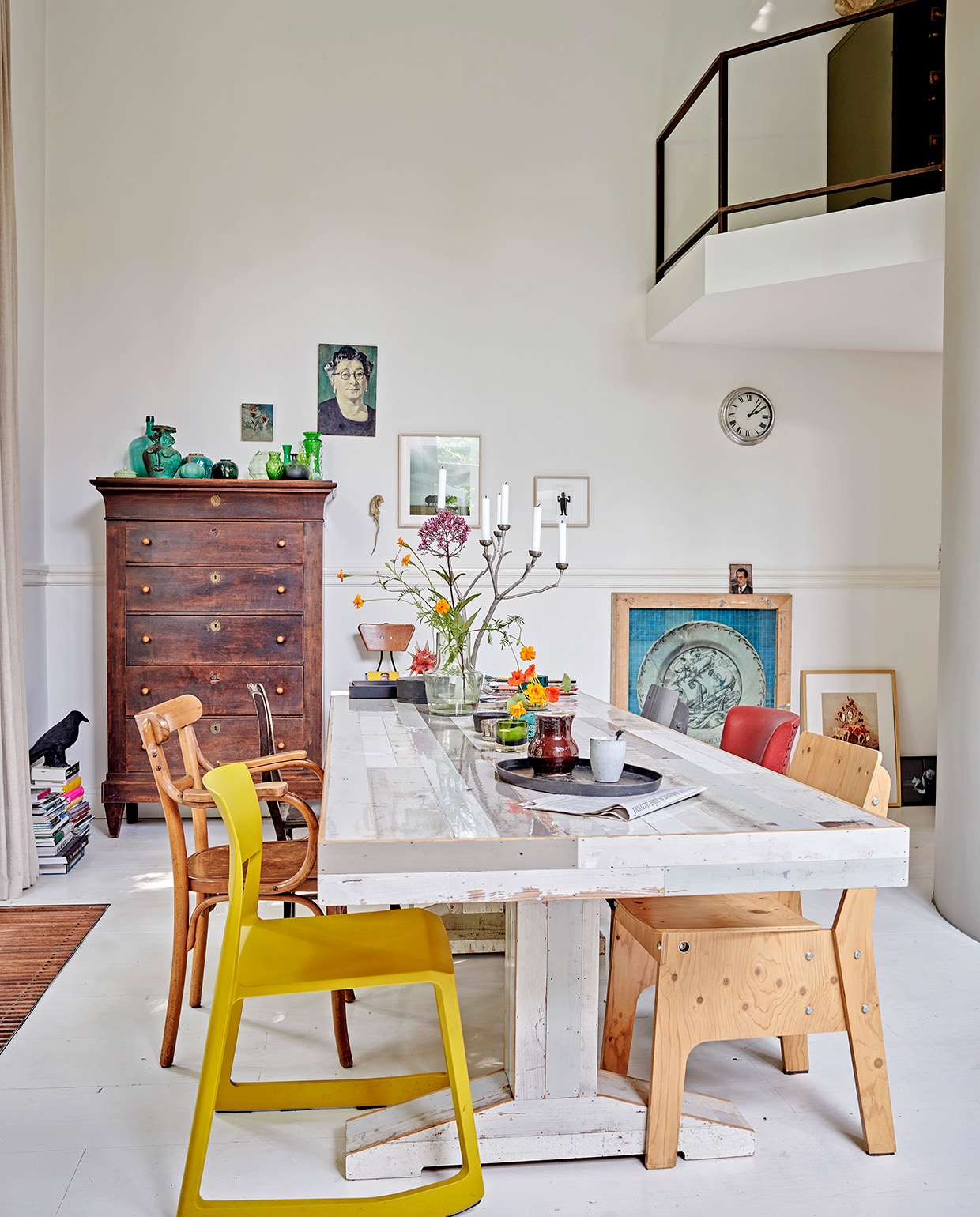 Oude grenenhouten vloer, wit geschilderd. Gele stoel Tip Ton van Vitra via Van Duivenboden. Eettafel Kantinetafel en stoel rechts voor Piet Hein Eek. Kandelaar Twiggy Large Sjakie’s. Kast Chiffonnière. Vogel raaf en dienblad Pols Potten. Kunst transfer op rijstpapier in houten lijst van Laurien Mulder. Papiermaché rat van Caroline de Bruijn. Vaas op tafel MrsBloom. Overig herkomst onbekend.