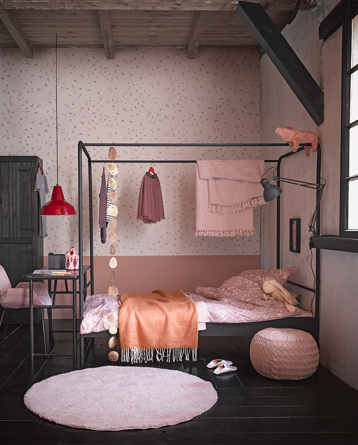 Zwarte grenenhouten kast Bunk, 200x120x37 cm (hxbxd) € 649,-. Zwartmetalen hemelbed Bunk, 125x206x190 cm (bxlxh) voor matrasmaat 120×200 cm, € 219,-. Ook in 95x206x190 cm (bxlxh) voor matrasmaat 90×200 cm € 199,- Verf Old Pink per liter € 18,95 M.m.v. Household Hardware (sloffen, roze mandje), Ikea (beddengoed, vloerkleed, roze plaid hangend aan bed, knuffelvarken, bureaulamp, kleurpotloden, grijs vilten mandje), Loods 5 (rode hanglamp, roze poef, oranje plaid, roze plaid eronder, streng parelmoeren schijven, knuffelkonijn, rode hangers), 10 days (kleding), Zuiver (roze stoel).