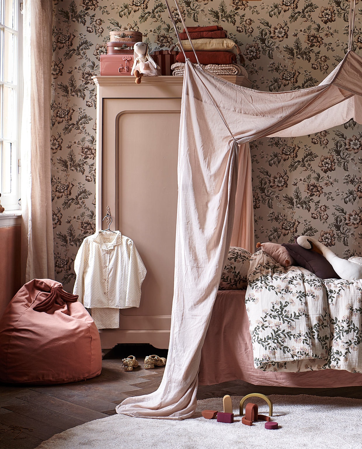 Juten vloerkleed Dots van Ferm Living (vtwonen.be). Dekbed- overtrek Honeysuckle Muslin van Garbo &amp; Friends, 140×200 cm (lidor.nl). Kussen in vorm van huis Celia Mink van Camomile London, gevlochten opberg-mand appelvorm van Ferm Living, miniatuur-items van Maileg: roze houten bed, keuken, badkamerwastafel, ballet dance room met big sister mouse (storeofdaydreams.com). Mini-schommel (feloufamilyhouses.nl). Roze ronde poppenhuistafel (maileg.com). Zwarte ronde poppenhuisstoelen (ilovespeelgoed.nl). Knuffel konijn, houten poppenhuismeubels bed, kast en stoel (zarahome.com). Wanddecoratie ballon Byon Dusty small (psikhouvanjou.nl). Stof voor gordijnen, roze gewassen linnen (kniphal.nl). Vloer visgraat eiken bruin geolied van vtwonen (karwei.nl).