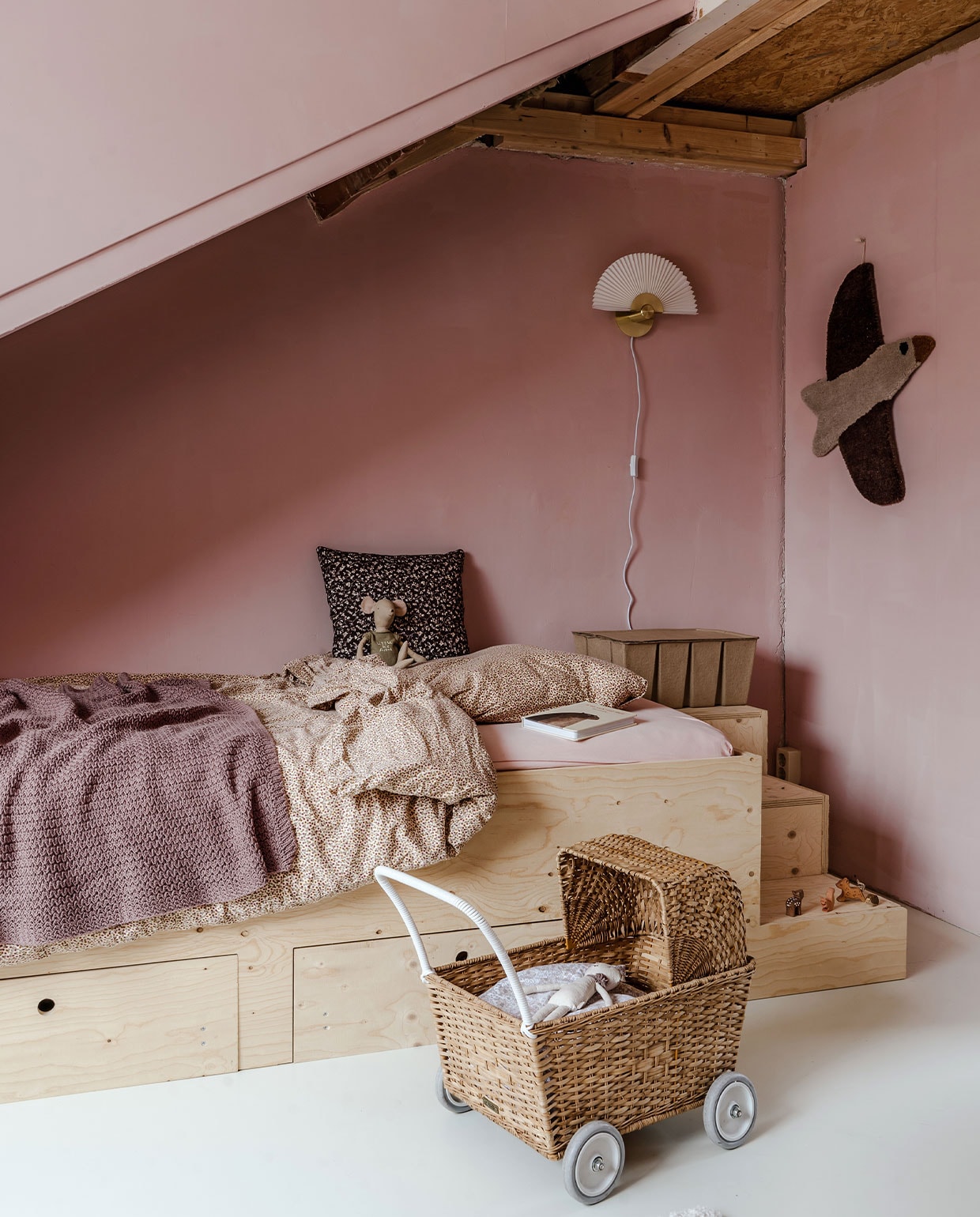 Kinderwagen Olli Ella, bedframe zelfgemaakt, plaid Bugaboo, dekbedhoes Konges Sløjd, kussen en stoffen wandkleed vogel Meri-Lou, muurlamp WK Home, vloer multiplex in kleur white No.201 van Farrow and Ball, muurverf Ballet Dancer van Histor, opbergdoos Jysk.
