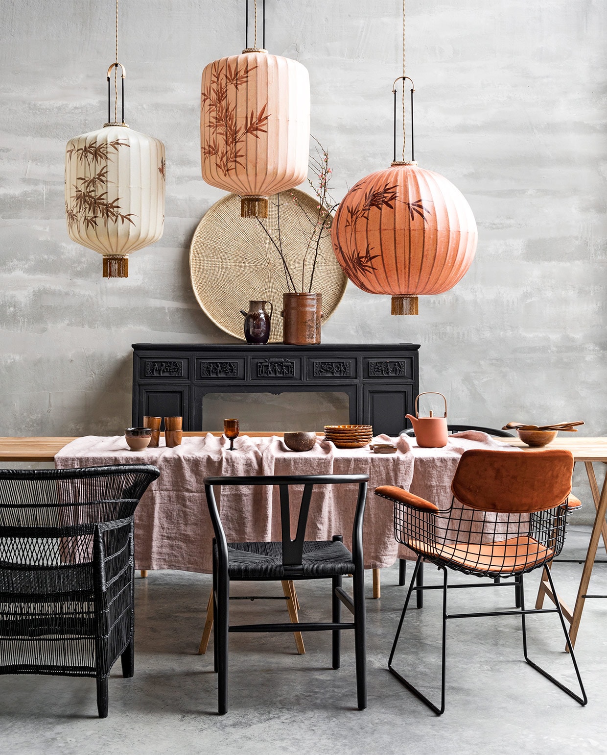 Teakhouten schragentafel 180x80x76 cm (lxbxh), wire stoel met steenoranje velours bekleding, lampion­lampen, terra ontbijtborden met streep, kokoskommen, soepkom met bovenrand van glazuur, kom met daarop houten lepels, kan met oor op de schouw (HK Living). Linnen tafelkleed in kleur pink salt, mokken uit de Merci collectie en theepot terracotta met houten handvat en dekselhouder(By Mölle). Handgeweven Lupane mand van palmblad uit Zimbabwe, Ø 100 cm (boxworx.nl). Houten stoelen met rieten zitting, rieten stoel uit Malawi (Netty de Groot). Keulse pot op schoorsteen privébezit.
