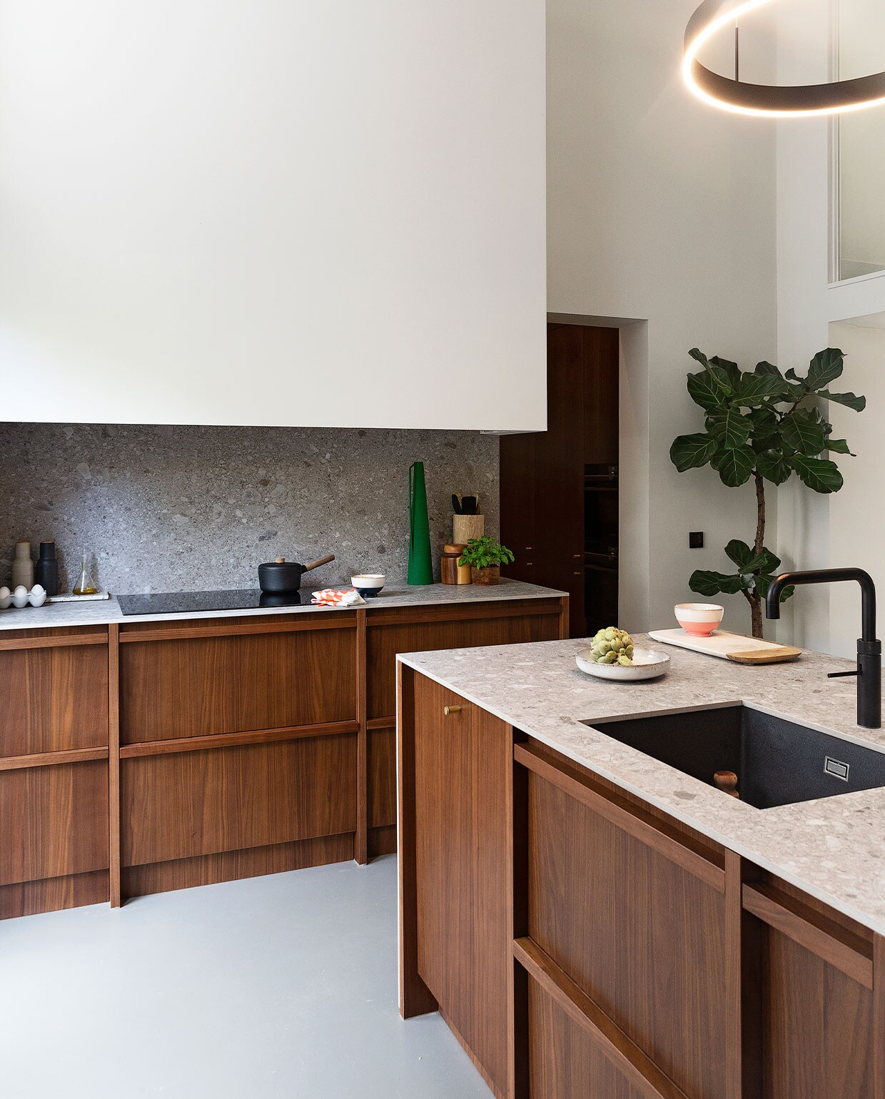 Keuken eigen ontwerp, keramieken bladen Mystone Ceppo di Gré greige van Marazzi. Kraan Quooker, wasbak Reginox. Hanglamp My Planet Led. Kastfronten Walnut van Aro. Kookplaat Aeg. Steelpan Eva Solo, dienblad en eierdoos Søstrene Grene, peper-en-zoutstel Menu, olijfoliefles Loods 5, houten pot met deksel Kinta, vijzel uit Marrakech, bakje Tica. Egalinevloer 2-componenten. Muurverf Ral 7030 van Fairf. Overig herkomst onbekend.