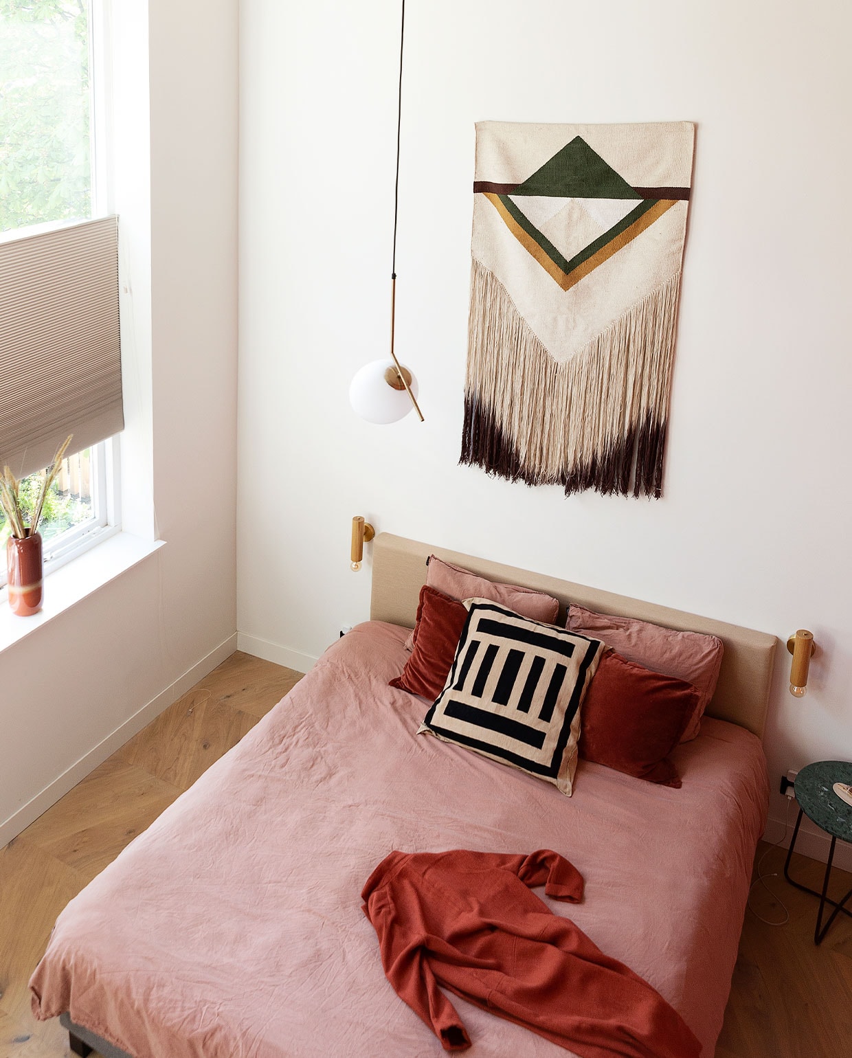 Bed Wehkamp, beddengoed La Redoute, bordeauxrode kussens Tica, gestreept kussen uit Zuid-Afrika. Ochtendjas H&amp;M. Bedlamp AliExpress, wandkleed HKliving. Hanglamp Ic Lights van Flos. Bijzettafel Dutchbone, vaas Tica, raambekleding in kleur Latte van Veneta. Eikenhouten vloer in Hongaarse punt. Muurverf kleur Leonie van Fairf.
