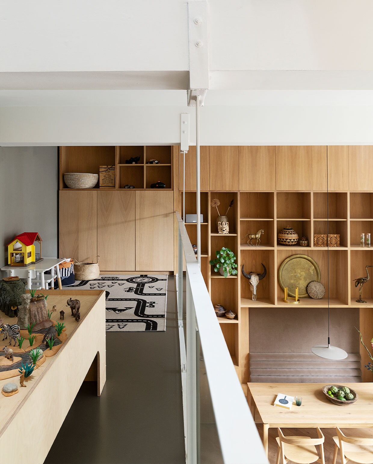 Eikenfineer wandkast eigen ontwerp in samenwerking met timmerman Thijs de Jong. Objecten van diverse reizen meegenomen. Speelkleed Wehkamp. Speeltafel gemaakt door Timmer Toko van Overdijk, speelgoeddieren en geel huisje Schleich. Witte tafel en kruk Playtive. Manden Ikea, ronde bak Return to Sender, hoge bak Kapla. Egalinevloer