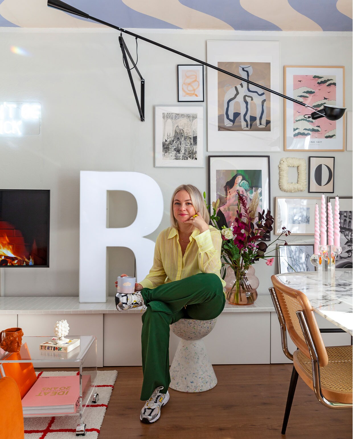 R lichtletter via Ebay Kleinanzeigen, kruk Wild Studio, koffietafel via Ebay, stoel Home24, lamp Flos, vaas Pols Potten, bruine beker zelfgemaakt, kaars Sentimental Candles, tafel Depot. Overig onbekend.