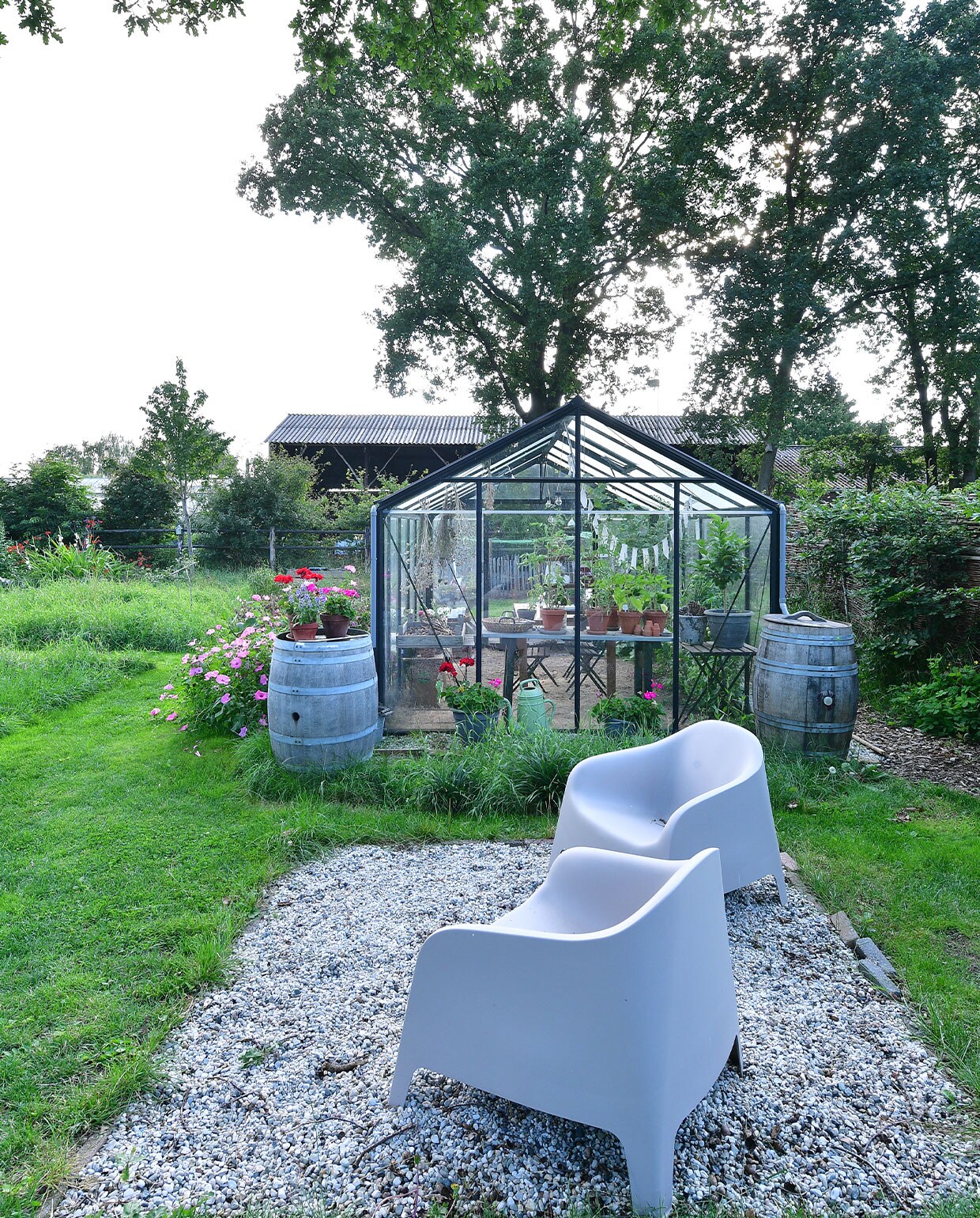 Wijnvaten, gekocht bij een Nederlandse wijnboer die ze over had, kregen een nieuw leven als regen- en sierton. Links staan Lavatera’s en dahlia’s. Stoelen Ikea.