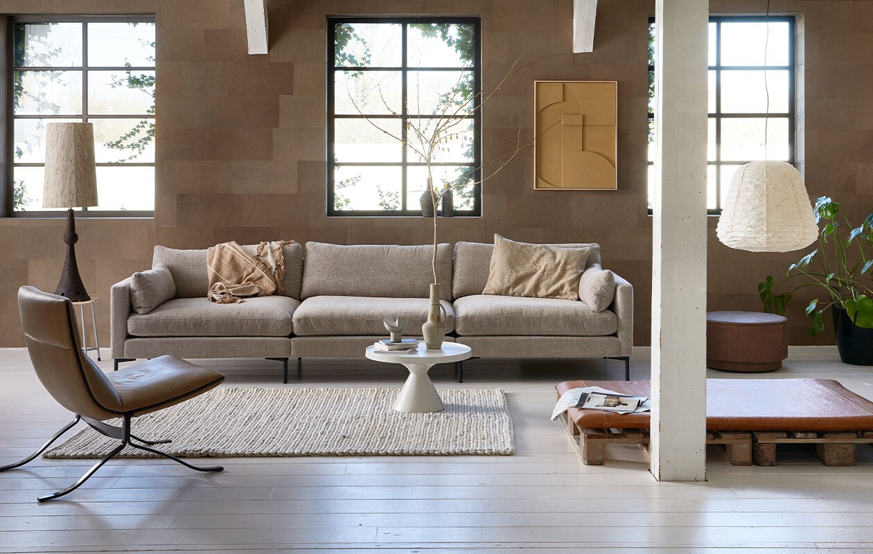 Leren wandtegels in kleur Desert, per m2 € 69,95 (enzopellini.com). Bank Summer in kleur Latte, 4,5 zits, 335 cm (b) € 2530,-, aluminium salontafel Floss, 60 cm (Ø) € 275,- (zuiver.com). Fauteuil Juno vanaf € 1549,- (eyye.nl). Handgemaakt wollen vloerkleed Hjorstvang, 160×230 cm € 349,- (ikea.nl). Leren loungemat, 100×6,5×150 cm (bxdxl) € 379,- (nahka.nl). Ecoleren poef van vtwonen in kleur Cognac, 60×36 cm (Øxh) € 159,-, plaid op bank Sahara van Malagoon, 150×125 cm € 59,95, papieren hanglamp Leena, 50×52 cm (Øxh) € 144,95, kussen, 50×70 cm € 41,90, vaasjes op vensterbank vanaf € 33,50 (vtwonen.be). Keramische voet schemerlamp € 195,- (neeflouis.nl). Kruk € 30,- (vandijkenko.nl). Aan de wand reliefkunstpaneel in kleur Sand, 63×83 cm € 469,-, lampenkap in zijde, naturel, 36×58 cm (Øxh) € 159,- (hkliving.nl). Overig privébezit.