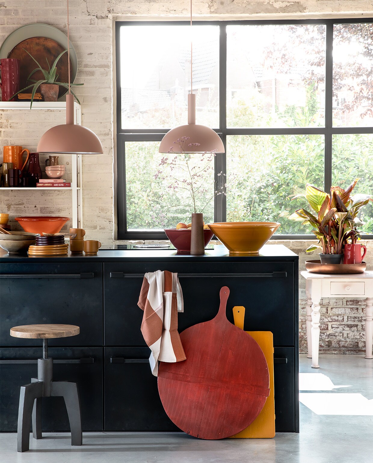 Zachtroze hanglampen Dome Shade van Ferm Living inclusief roze fitting high (vtwonen.nl). Draaikruk Space van BepureHome (Woondock). Grote oude kaasplanken (H&amp;M Home), gelakt met Perfection zijdeglans lak in dieprood en mosterdgeel (Histor). Theedoek okergele kopjes , okergele borden, donkerpaarse borden per stuk (H&amp;M Home). Okergele schaal, donkerrode schaal (In-Petto). Beige schalen (Intratuin). Bovenop de kast: grote donkerrode kan(In-Petto), theedoeken in okergeel en donkerpaars (H&amp;M Home), koper­kleurige schaal van BePureHome , zachtgroene schaal (Woondock). Midden in de kast: zachtroze schaaltjes, okergele kan (In-Petto). Donkerpaarse kopjes (H&amp;M Home). Donkerrode karaf Nikki, lichtbruine karaf (Intratuin). Beige kan (Intratuin). Onder in de kast: terracotta schaal, okergele diepe borden (In-petto). Zachtroze tafeltje (Combitex). Koperkleurige schaal Big Waitress van BePureHome (Woondock). Donkerrode kleine kan (In-Petto). Kamerplanten Canna Hybride (Intratuin). De keuken is een eigen ontwerp van de bewoners, binnenwerk van hout, blad en kasten afgewerkt met blauw staal. Overig privébezit.