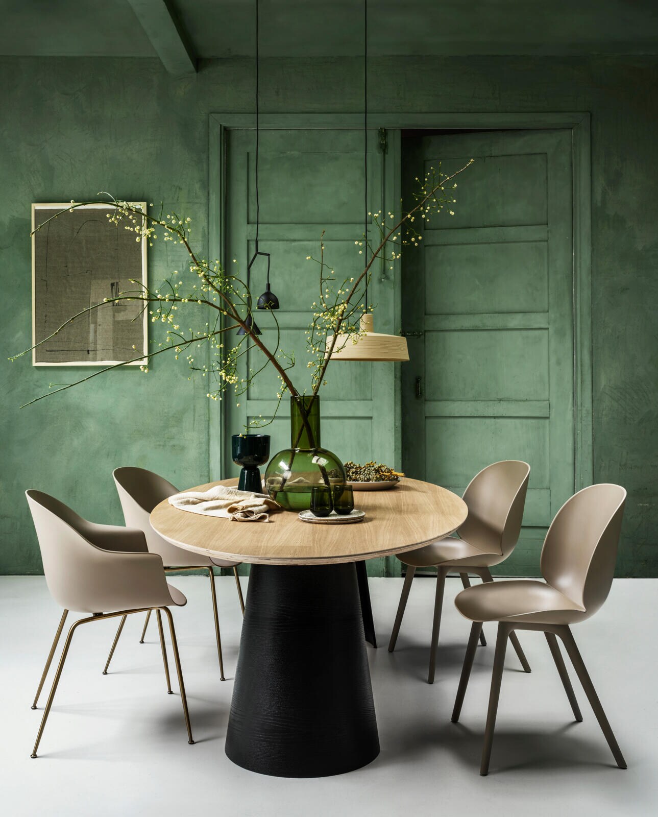 Tafel van eiken fineer met onderstel van eiken fineer houten poten halve kegelvorm hol en bovenblad ovaal, afmeting 260 x 120 cm en hoogte 75 cm, ontwerp Arp € 2225,00 (loods5.nl)Stoelen van Gubi in zand, rechts beetle met poot in zand € 369,00 en links bat dining € 349,00 (vtwonen.nl)Lamp met 2 vormen zwart van Menu € 249,00 (vtwonen.nl)Lamp zand mat met kalkachtige verfstrepen oppervlak soho 38 led van Marset € 574,00 (vtwonen.nl)Textielkunst ingelijst van Fant vanaf € 495,00 (sukha.nl)Vaas groen glas van hkliving €99,95 ( vtwonen.nl)Planten pot aardewerk donkergroen op voet van Iittala € 69,00 (iittala.com)Groene waterglazen per 2 stuks van Iittala € 64,90 (iittala.com)Borden en schaal van keramiek vanaf € 35,-(sukha.nl)Tafelkleed in linnen van vtwonen collectie € 79,95 (vtwonen.nl) vtwonen 01-2021 | Fotografie Stan Koolen, styling Marianne Luning