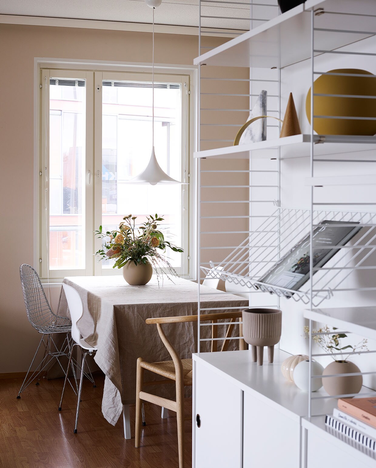 Wandrek String. Eettafel van maatwerkblad op schragen van Hay. Stoelen Vitra (metaal) en Flinders (hout). Vazen en kommen Cooee. Hanglamp Gubi.