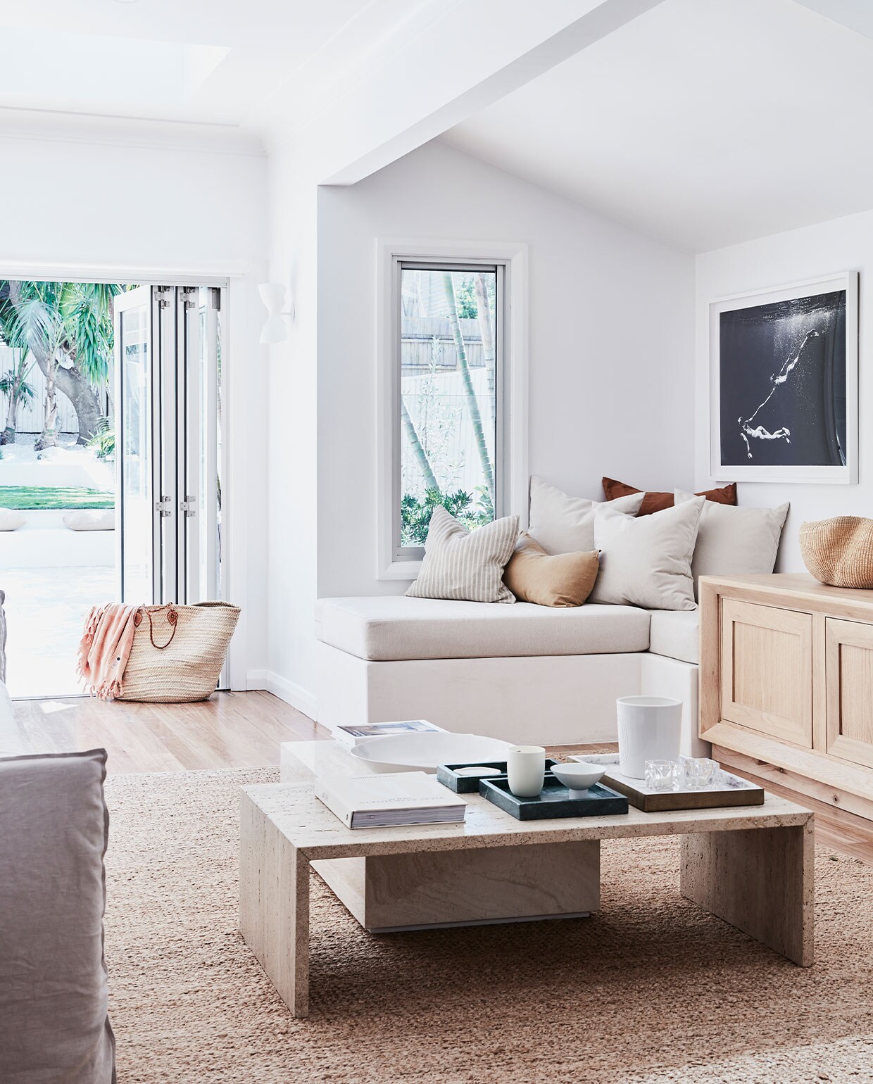 Bank met opbergruimte op maat gemaakt. Kussens Grace Garrett. Dressoir MCM House. Salontafel en vloerkleed Armadillo. Kunstwerk Kate Bellm. Dienbladen Country Road. Muurverf Lexicon van Dulux. Overig onbekend.