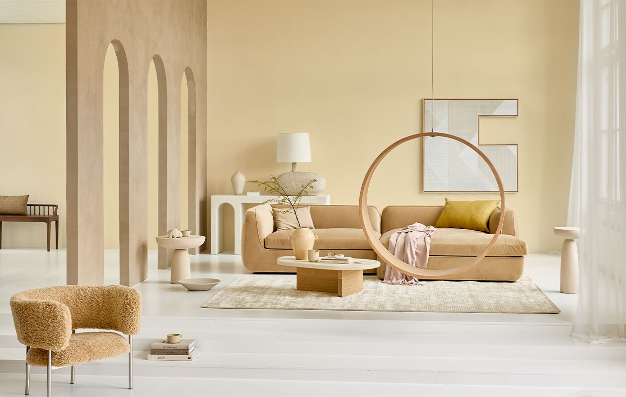 Op de muur krijtverf Estate Emulsion Farrow’s Cream 67 van Farrow &amp; Ball, 2,5 liter € 97,- (paint-paper.nl). Bank Bowie Juke Sand corner sofa divan right, 296x170x72 cm vanaf € 3108,- (festamsterdam.com). Microcement sidetable vanaf € 1850,-, schemerlamp € 590,- (lanena-home.com). Fauteuil Font Bold van Møbel-Copenhagen bekleed met honinggele schapenvacht € 3231,- (roosdesign.eu). Salontafel Mush met eikenhouten onderstel en gesmeerd blad, 105x60x30 cm (lxbxh) € 649,- (aedamanthony.nl). Ronde eikenhouten hangstoel Swing no 2 van Iwona Kosicka, prijs op aanvraag (kosicka.pl). Viscose vloerkleed met ingeweven streepreliëf van HKliving, 300×200 cm € 845,75 (vtwonen.nl). Gele vaas € 69,95 (urbannatureculture.com). Mok, set van twee vanaf € 90,-, kan van gedraaide klei vanaf € 70,- (byjoa.nl). Linnen kussen, 50×70 cm € 120,- (couleurlocale.eu). Microcement bijzettafels, 50×50 cm € 702,-, 30×61 cm € 618,- (edha-interieur.nl). Kunstwerk aan de muur van Matthias de Vogel, 120×120 cm prijs op aanvraag (faultlineslab.com). Roze plaid € 49,99, katoenen kussenhoes, 30×50 cm € 7,99 (zarahome.com). Houten bank Oak Spindle, 150x35x60 cm (bxdxh) € 669,- (ethniccraft.com). Overig privébezit.