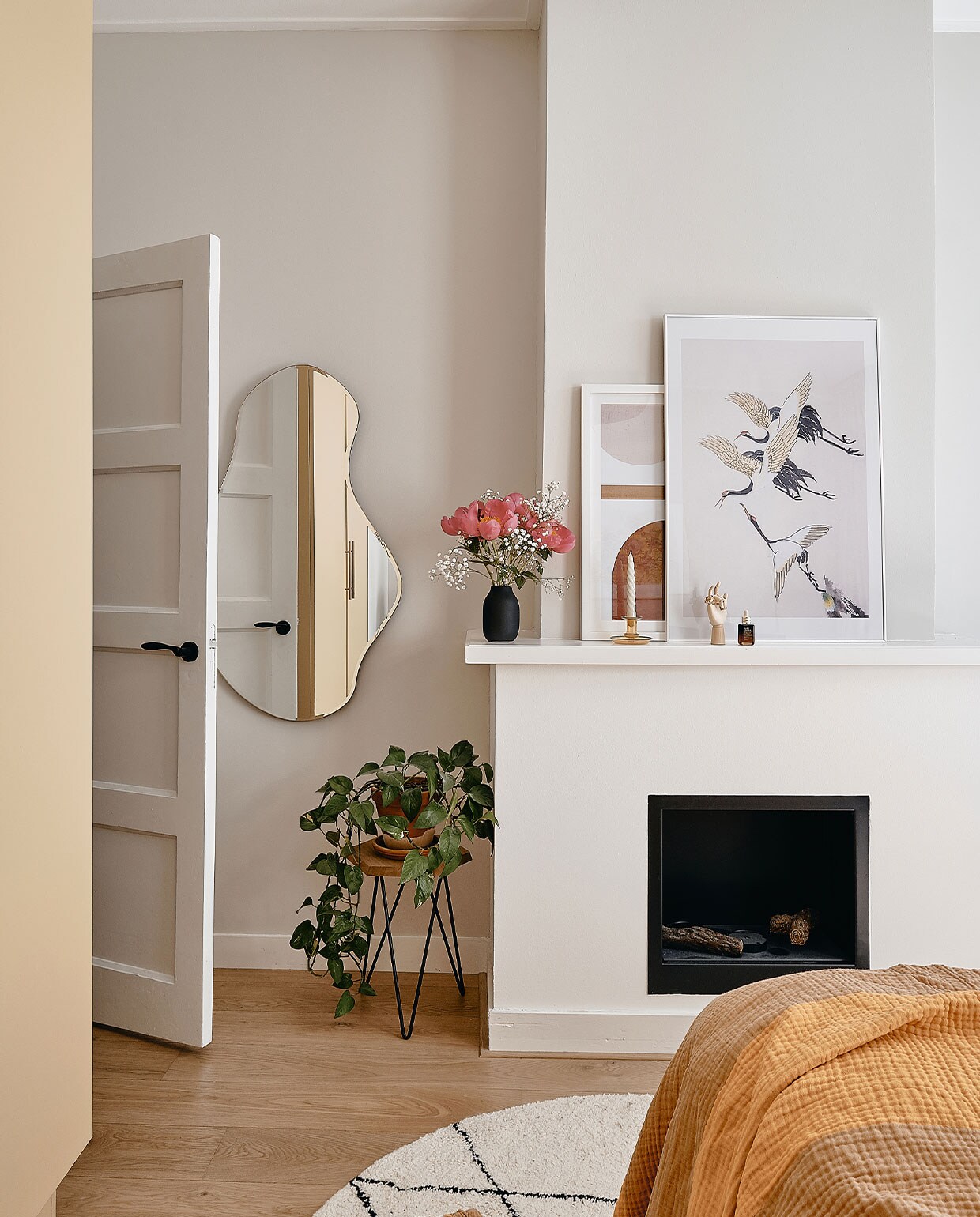 Spiegel Pond van Ferm Living. Bijzettafel Loods 5. Zwarte vaas Blomus. Prints Juniqe, kandelaar, houten hand en bedsprei Hay. Vloerkleed Benuta. Kast Pax van Ikea, geverfd in Hay van Farrow &amp; Ball.