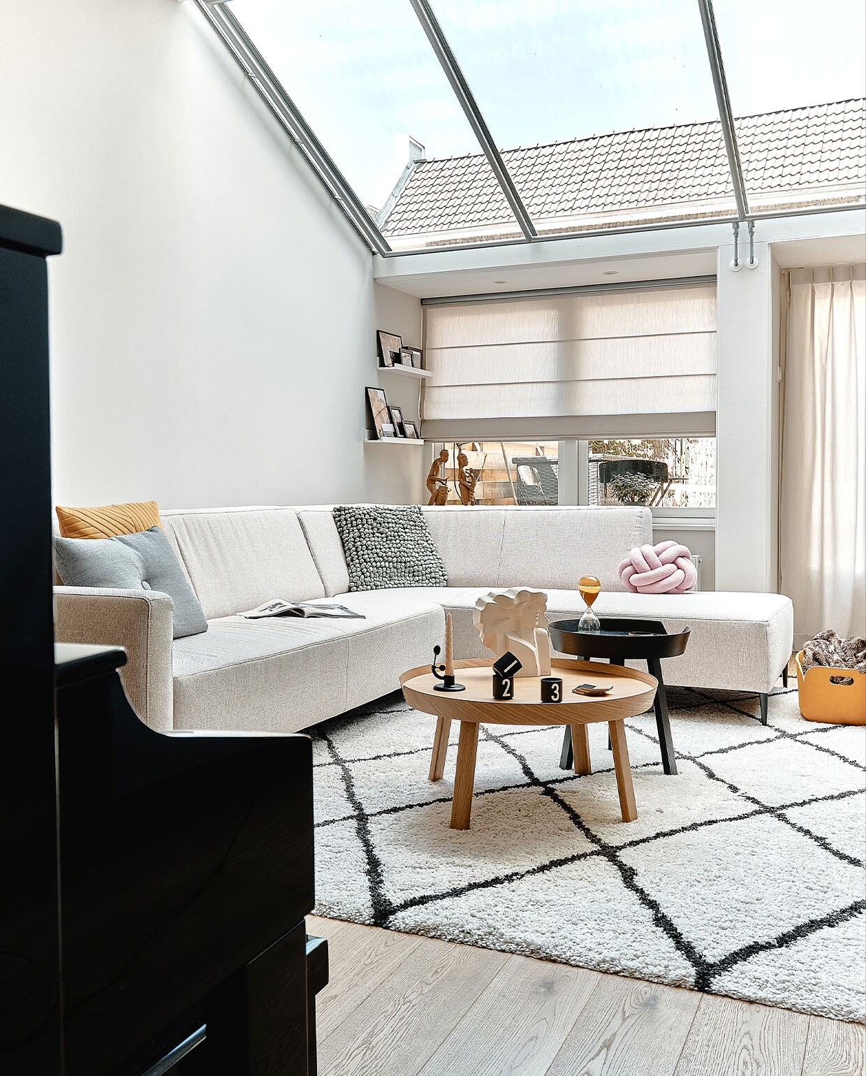 Muurverf Ammonite van Farrow &amp; Ball. Bank Goossens. Grijs en geel kussen Hay, bolletjeskussen 2LIF en knoopkussen Westwing. Vloerkleed Benuta. Salontafels en gele opbergbak Muuto, kandelaar Ferm Living, espressokopjes Design Letters. Beeld Alain Hubinont en houten beelden in vensterbank van Maartens ouders. Zandloper Hay.