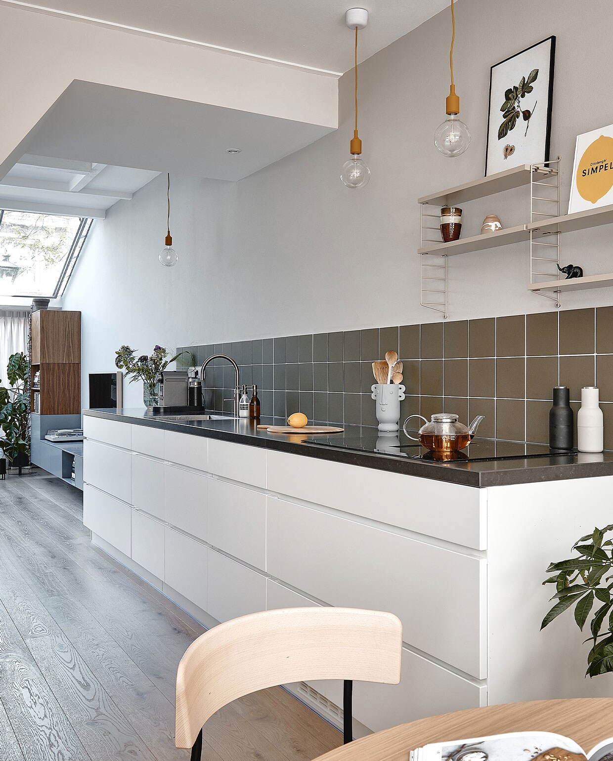 Muurverf Purbeck Stone van Farrow &amp; Ball. Wandtegels Winckelmans 15×15 cm in kleur Australian Green. Keuken Mano van Kvik met werkblad Jetstone Raven Satin van 40 mm. Hanglampen E27 Muuto. Vaas cadeau gekregen, theepot Simon Lévelt, peper-en-zoutstel Menu. Wandrek Pocket van String Furniture.