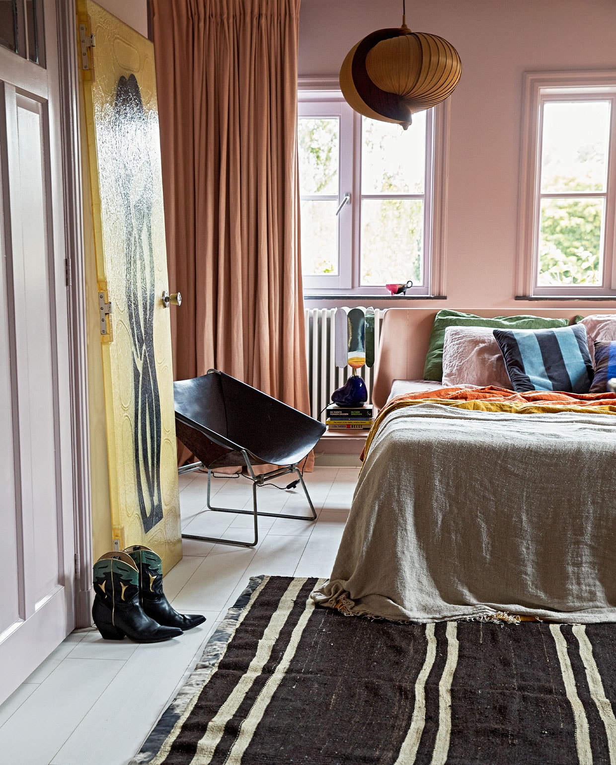 Verf wand Peach Blossom van Little Greene. Gordijnen Soft Salmon Amor Linnen van Vadain. Fauteuil Midcentury design van Pierre Paulin Polak, plafondlamp vintage Moon van Hans Agne Jakobsson, kunststuk tegen wand Fiberglass Deur Midcentrury via Best Wel Hip. Lamp nachtkastje voet van Ferm Living en kap van Hay. Bed Auping. Sprei HKliving. Kussens bedlinnen van Casa Comodo. Kleed Turks vintage. Laarzen Elena Iachi. Overig onbekend.
