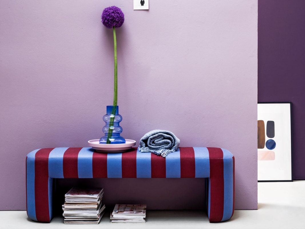 Muurverf Washed Lilac van vtwonen (vtwonen.be). Bankje Lobby bench, 140x40x45 cm (lxbxh), hanglamp, roze schaal (hkliving.nl). Ovaal vloerkleed in kleur nude roze van HK Lving, 240×150 cm, vaas Balloon van Normann Copenhagen (vtwonen.be). Plaid (malagoon.com). Poster nr. 8 van Berit Mogensen, 50×70 cm, lijst (theposterclub.com).