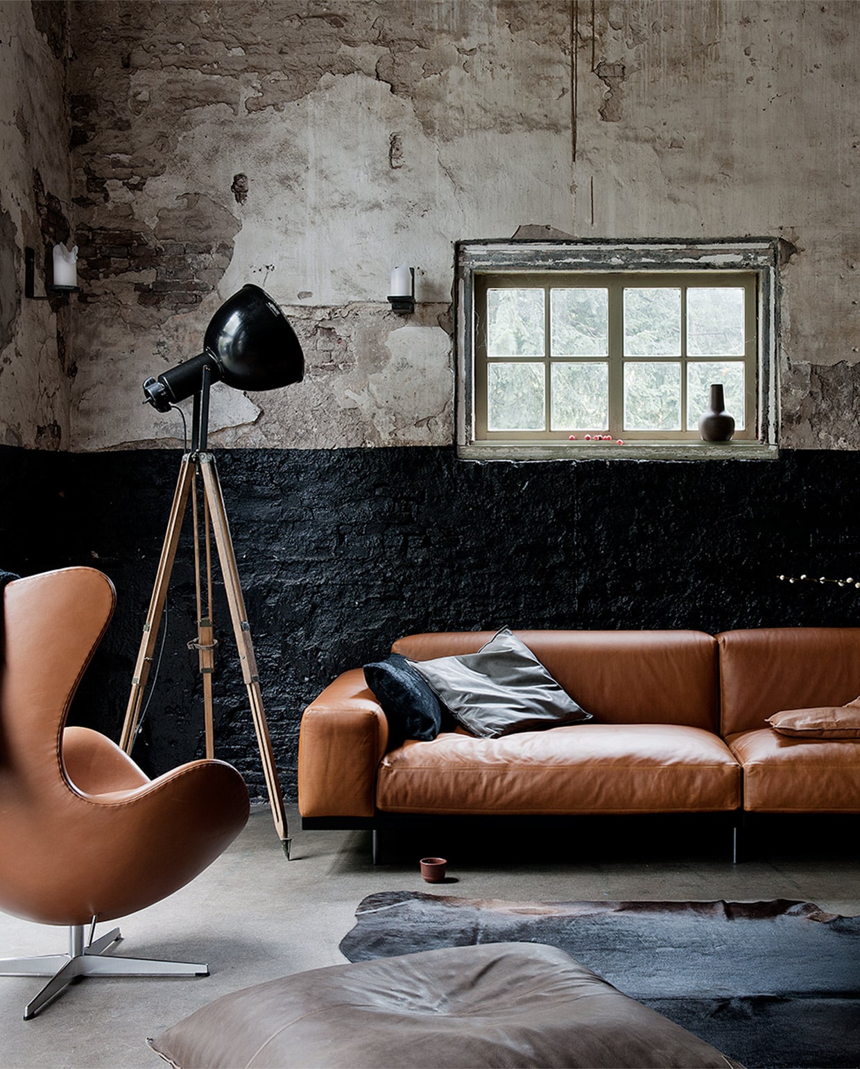 Leren bank van Arflex (Friday Next). Eggchair ontwerp Arne Jacobsen in hoge kwaliteit leer (Mobilia). Salontafel van gymnastiektoesteL (Meker Wonen). Vloerlamp, (Neef Louis). Zitzak (Heronymus). Koeienkleed (Van Buren). Kussens (Philomijn). Vaas van aardewerk (Maison NL). Klein vaasje in vensterbank (Neef Louis). Kommetje op de grond (The Frozen Fountain). Sjaal (Studio Ruig).