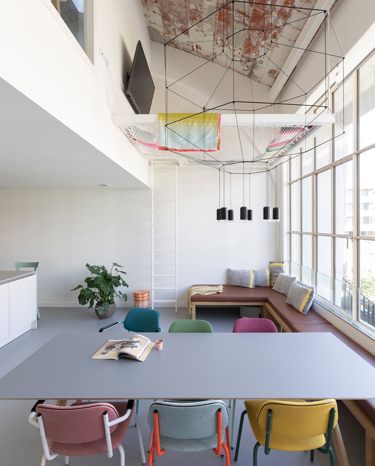 Hangnet Loftnets op maat gemaakt, frame en ladder laten maken door ingenieursbureau Onderwaater. Eettafel CPH30 van Hay, eetstoelen Lande Jami van Artifort, lamp boven eettafel Wireflow van Vibia. Gietvloer Bruizt. Raambank op maat gemaakt door Combo Design. Plaid op hangnet Hay. Kussens Colour Cushions van Hay.