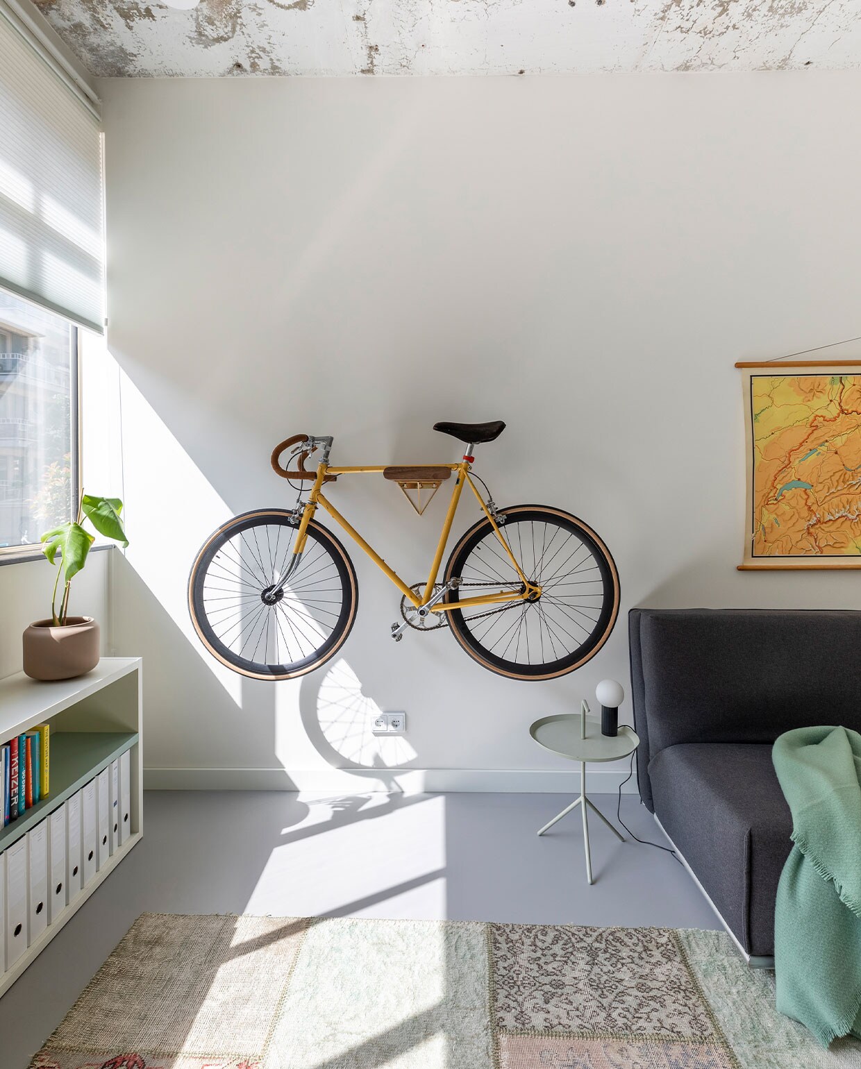 Fiets refurbished door Lievens Bikes. Slaapbank Natalie van Pfister (Zwitserland). Bijzettafel Hay. Lage kast met eraan vast bureau Sangiacomo, op maat gemaakt door Combo Design. Schoolkaart Zwitserland vintage. Vloerkleed patchwork van oude, geverfde Perzische tapijten.