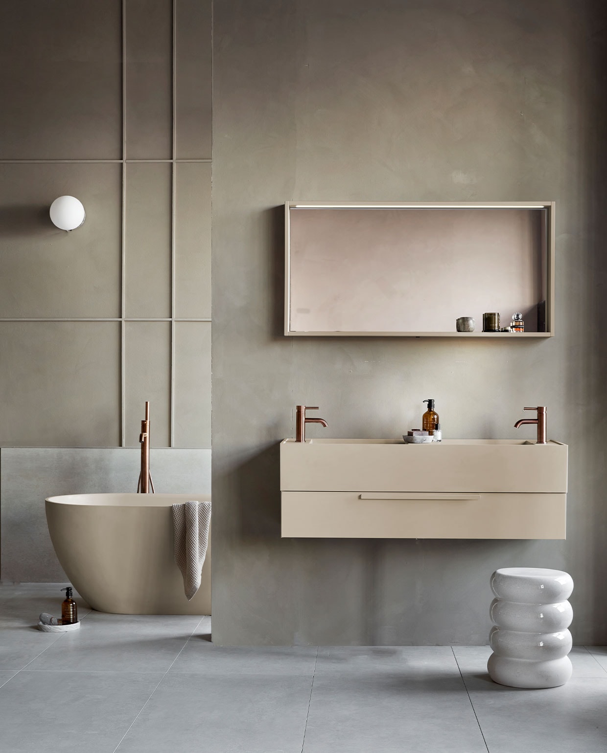 Kunststof spiegel Gorgeous in zand, inclusief ledstrip met bewegingssensor, 59,6x120x10 cm (lxbxd) (ook verkrijgbaar in breedtematen 60 cm en 90 cm en in wit, grijs en zwart). Top Solid wastafel Wide in zand, 40x121x20 cm (lxbxd)  (ook verkrijgbaar in breedtematen 61 cm en 91 cm, in wit en in Quartz en Marmer). Kunststof afdekblad in mat zand, 120 cm . Kunststof onderkast Tidy in zand, 1 lade met handgreep, 20x120x40 cm (lxbxd) (ook verkrijgbaar in breedtematen 60 cm en 90 cm en in wit, grijs en zwart). Top Solid bad Endless in zand, 160x73x57 cm (lxbxd), inhoud 200 liter  (ook verkrijgbaar in Quartz, grijs en zwart). Op vloer tegels Raw Sand van vtwonen, 60×120 cm. Achter bad vtwonen tegels Raw Sand, 80×80 cm  M.m.v. vestingh.nl (kleur op de muur Brown Wood No. 222), vtwonen.be (wandlamp TR Bulb van Menu, kruk Chubby van Pols Potten), nordal.eu (rond marmeren plateau), zarahome.com (geurkaars in glas, zeeppompjes, zeepschaaltje, handdoek), stories.com (parfum), hotbath.nl (messing kranen). Overig privébezit.