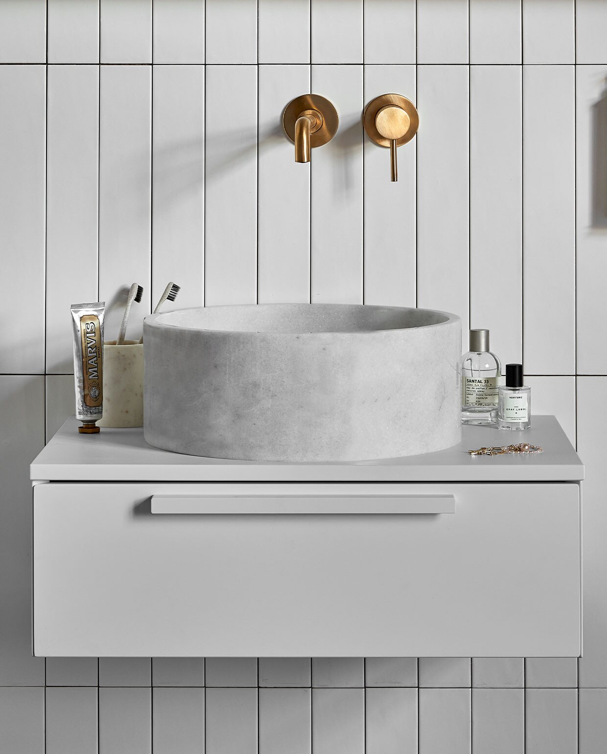 Marmeren waskom Circle in wit, 37×15 cm (Øxh) € 480,- (ook verkrijgbaar in bruin, zwart en zilvergrijs en in Top Solid en Quartz). Kunststof afdekblad in wit, 60 cm € 120,-. Kunststof onderkast Tidy in wit, 1 lade met handgreep, 20x60x40 cm (lxbxd) € 515,-. Op de wand vtwonen tegels Marrakesh Nieve mat, 6,5×40 cm, per m² € 70,-.