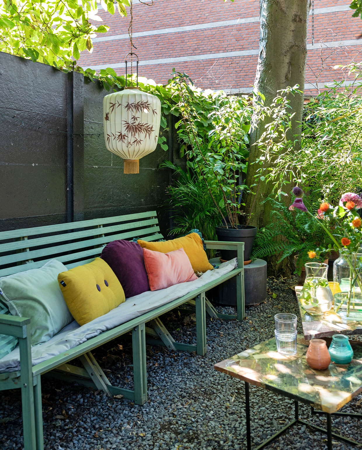 Bank Weltevree. Linnen dekbedovertrek By Mölle. Kussens van links naar rechts: HKliving, Hay, Sissy-Boy, Søstrene Grene, H&amp;M Home. Lampion HKliving. Betonnen ronde bijzettafel House Doctor, vierkante bijzettafels en karaf vintage. Buitenkaarsen Bolsius, glazen Serax, vaas vtwonen.