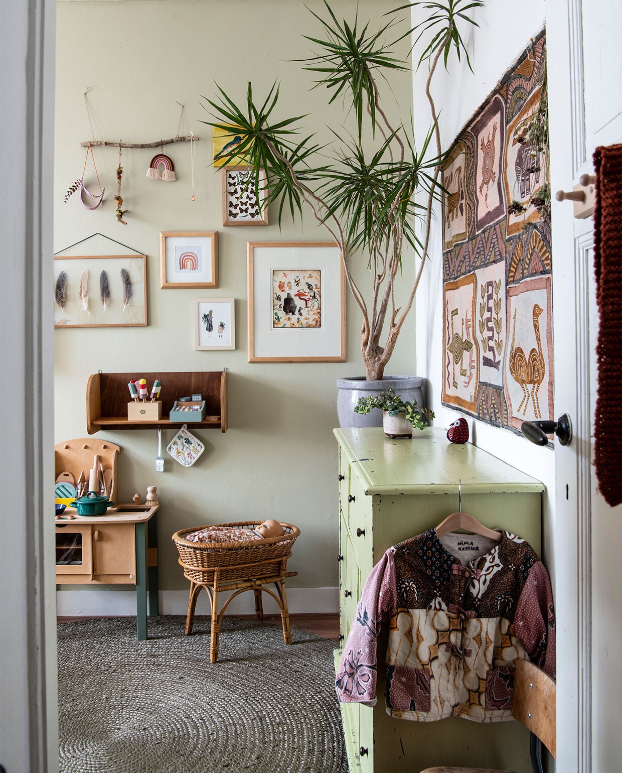 Ladekast, rieten poppenwieg, houten wandplank, plantenpotten tweedehands. Speelkeuken Marktplaats. Lijsten Fine Store, veren Hopi-Navajo. Regenboogprint Zoë, moeder &amp; dochter Saar Manche, dieren Marije Tolman. Kleed Woon Express. Wandkleed Marktplaats. Muurverf Toegankelijk van Histor. Planten Dracaena, sedum. Overig herkomst onbekend.