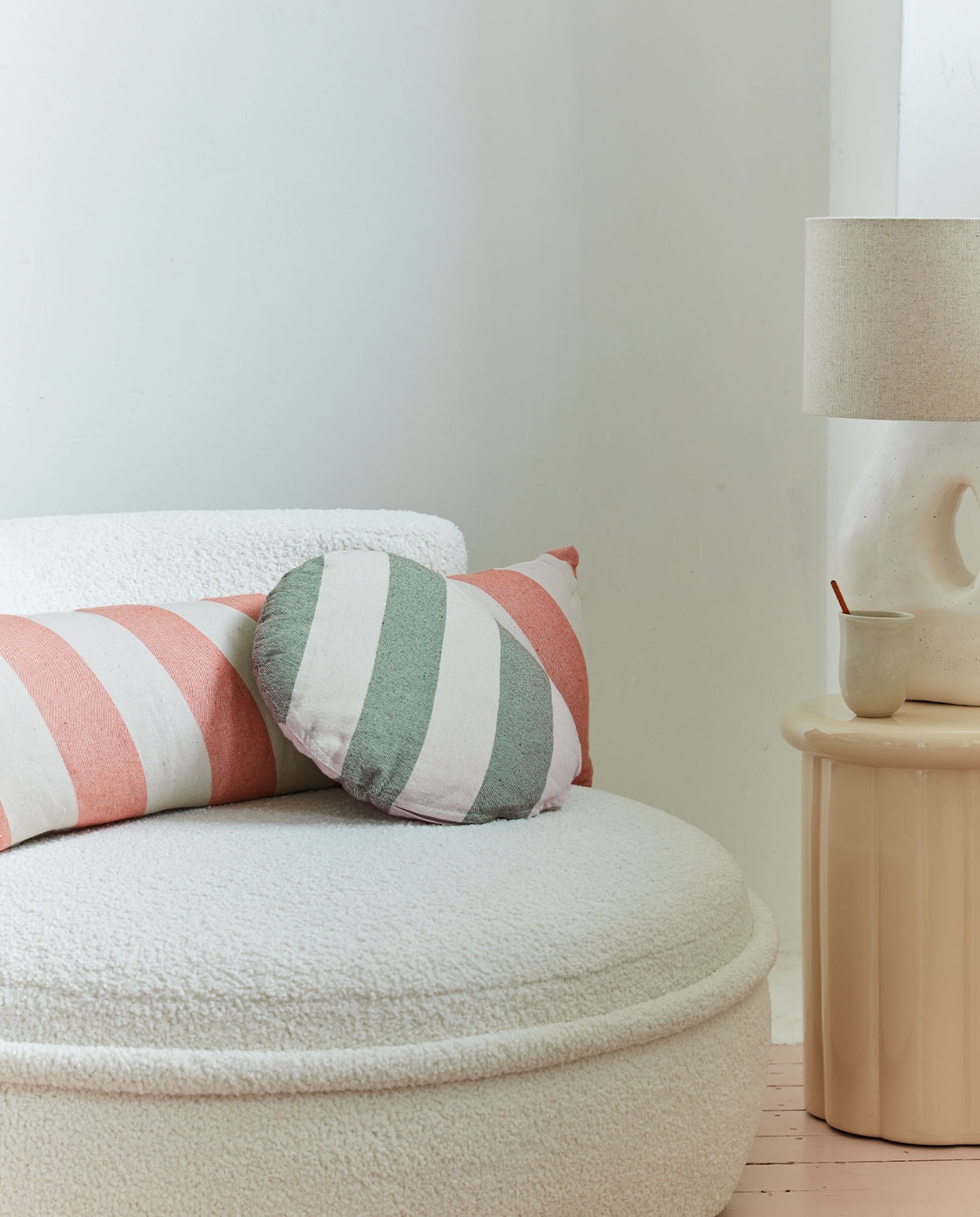 Kussen Bold Long, acryl en polyester, kleur Peach, 30×90 cm . Kussen Bold Round, acryl en polyester, kleur Green, 40 cm (Ø) (ook verkrijgbaar in Peach).M.m.v. loods5.nl/goods (fauteuil).