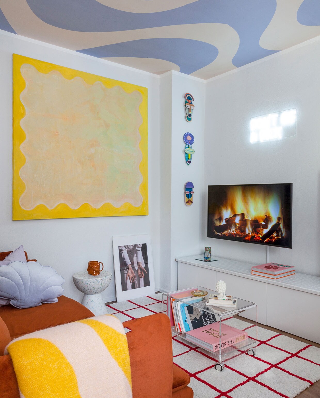 Behang op het plafond Curvy van Belarte Studio. Vloerkleed Ikea en koffietafel via Ebay. Bank Söderhamn van Ikea, hoes van Dekoria. Plaid Arket, kussen Moi Mili. Kruk Wild Studio, bruine beker en schilderij zelfgemaakt, kaars Sentimental Candles. Wandobjecten Studio Roof. Overig onbekend.