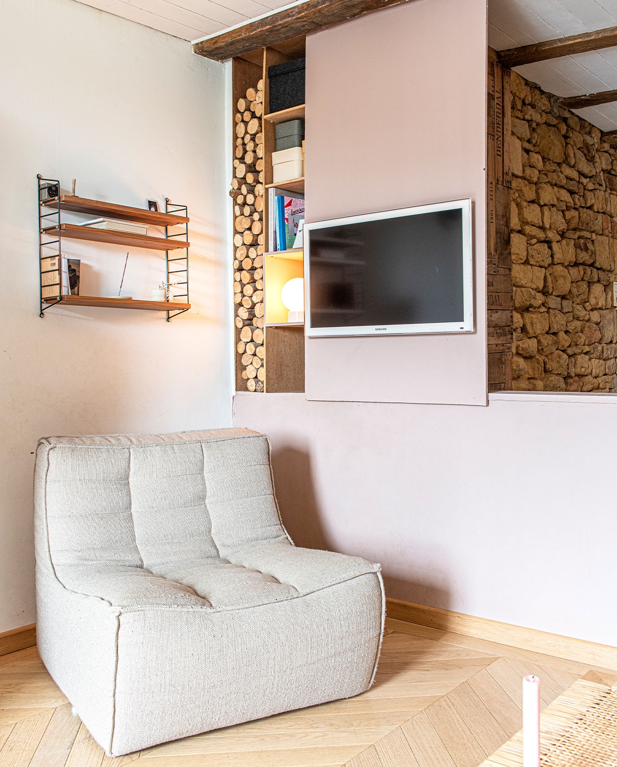 Fauteuil Ethnicraft, wandrek String Furniture, vloer eiken parket, televisie Samsung, kandelaar zelfgemaakt.